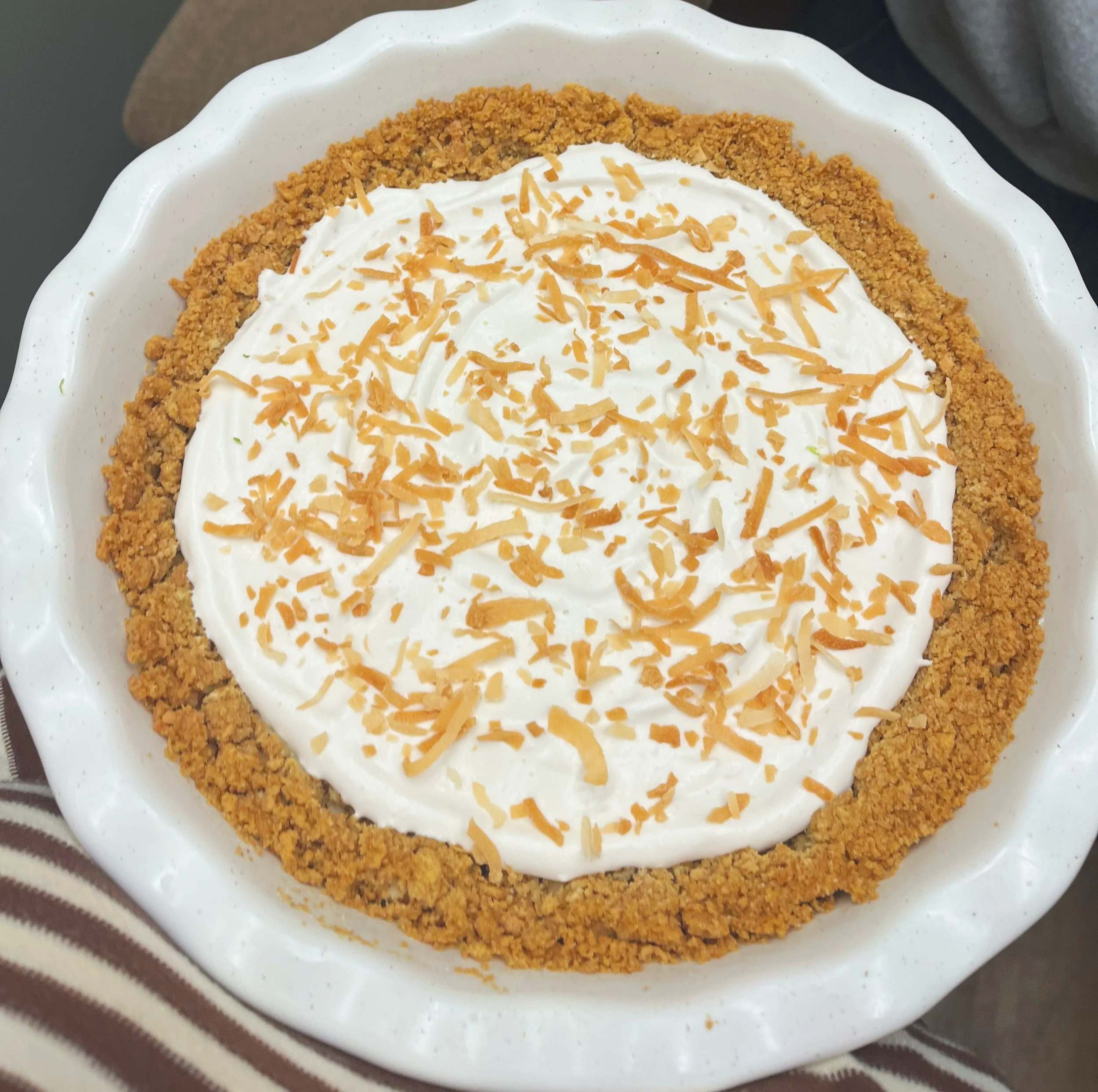 A key lime pie topped with coconut whipped cream