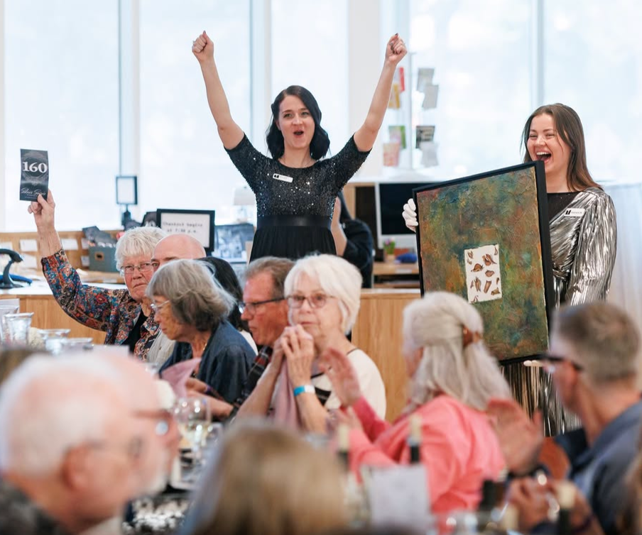 Amanda Lowry Wiberg holding an image just sold at an art auction