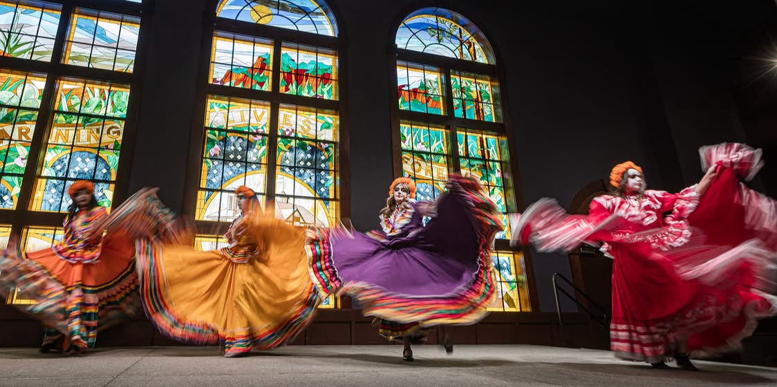 Women performing a traditional dance in traditional dress at a Day of the Dead event