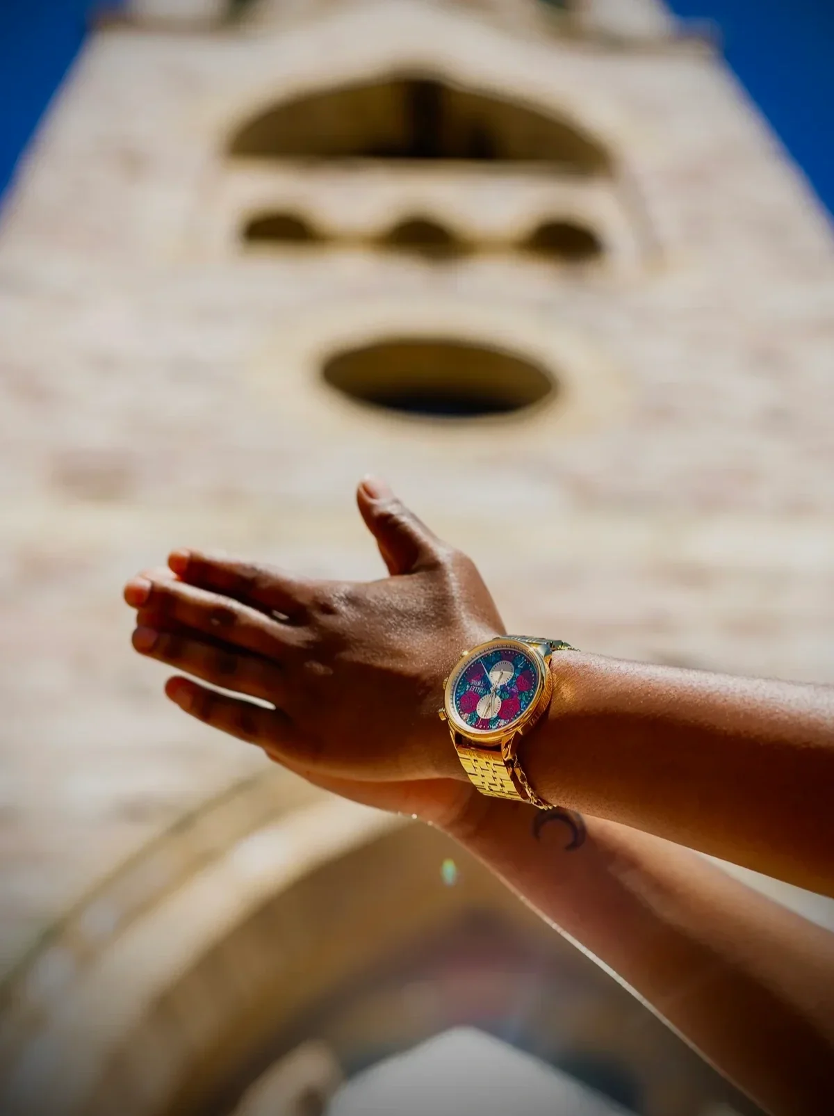 Close up of wearing a Talley and Twine Women's Exclusive Stained Glass Gold wristwatch with the Christ the Redeemer statue in Rio de Janeiro Brazil in the background
