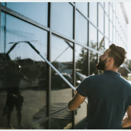 Man cleaning glass exterior of a building with a squeegee.