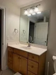 Bathroom vanity with a mirror, light fixture, wooden cabinet, sink, and faucet