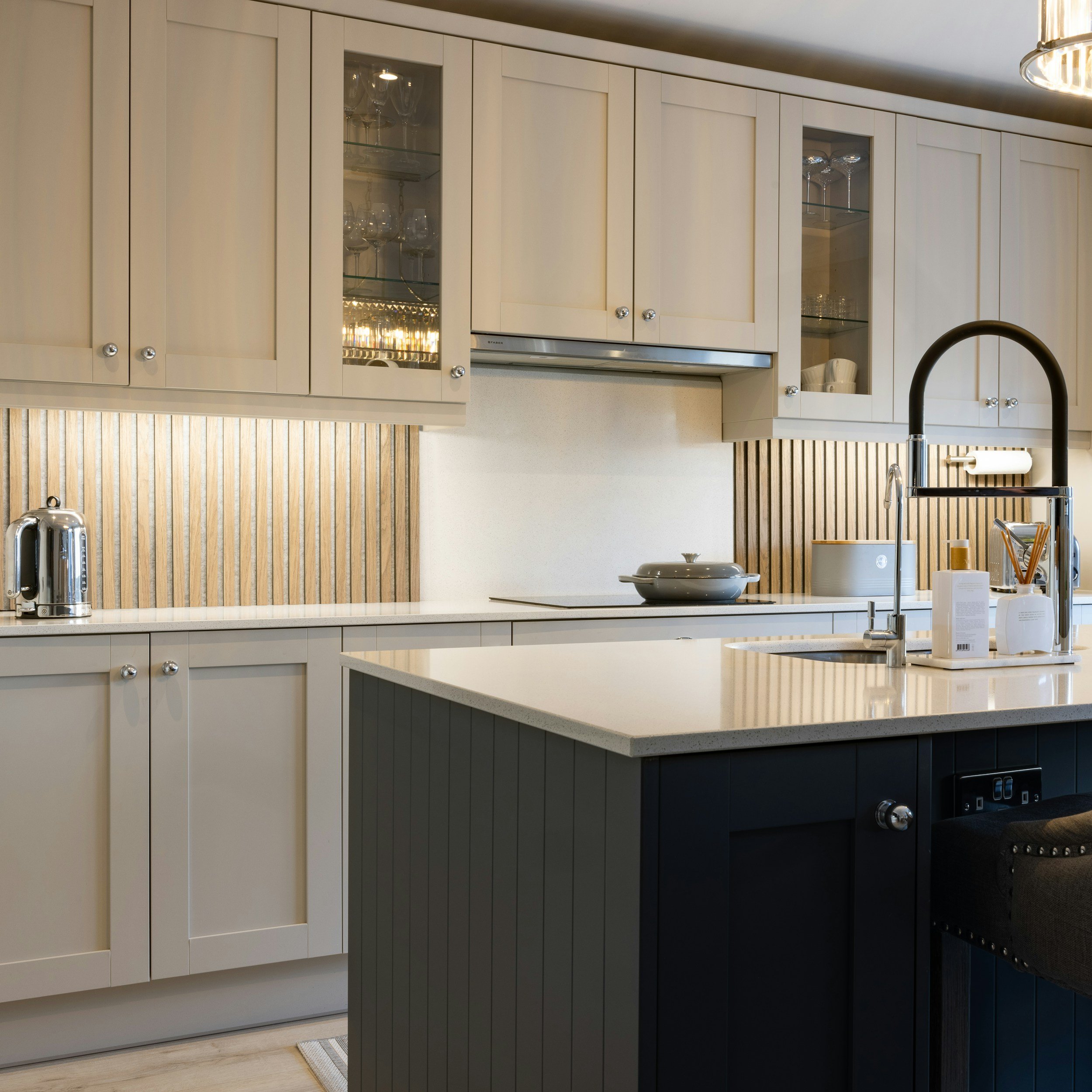 Modern kitchen with white cabinets, a black island, and wooden backsplash.