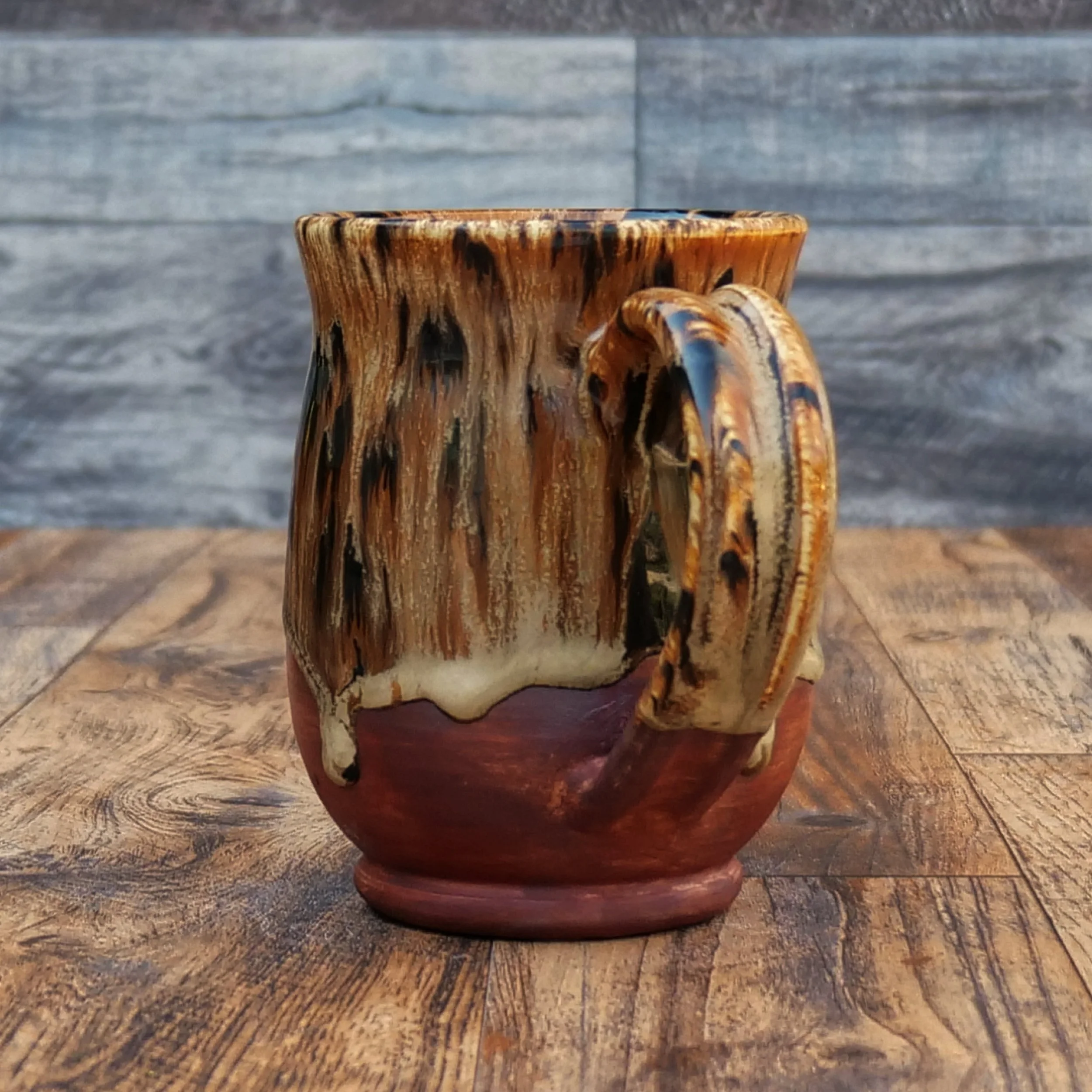 Handmade Emberbark Mug by Elderkiln Ceramics featuring layered bark-inspired glazes, flowing earthy tones, and a warm iron-red stoneware base.