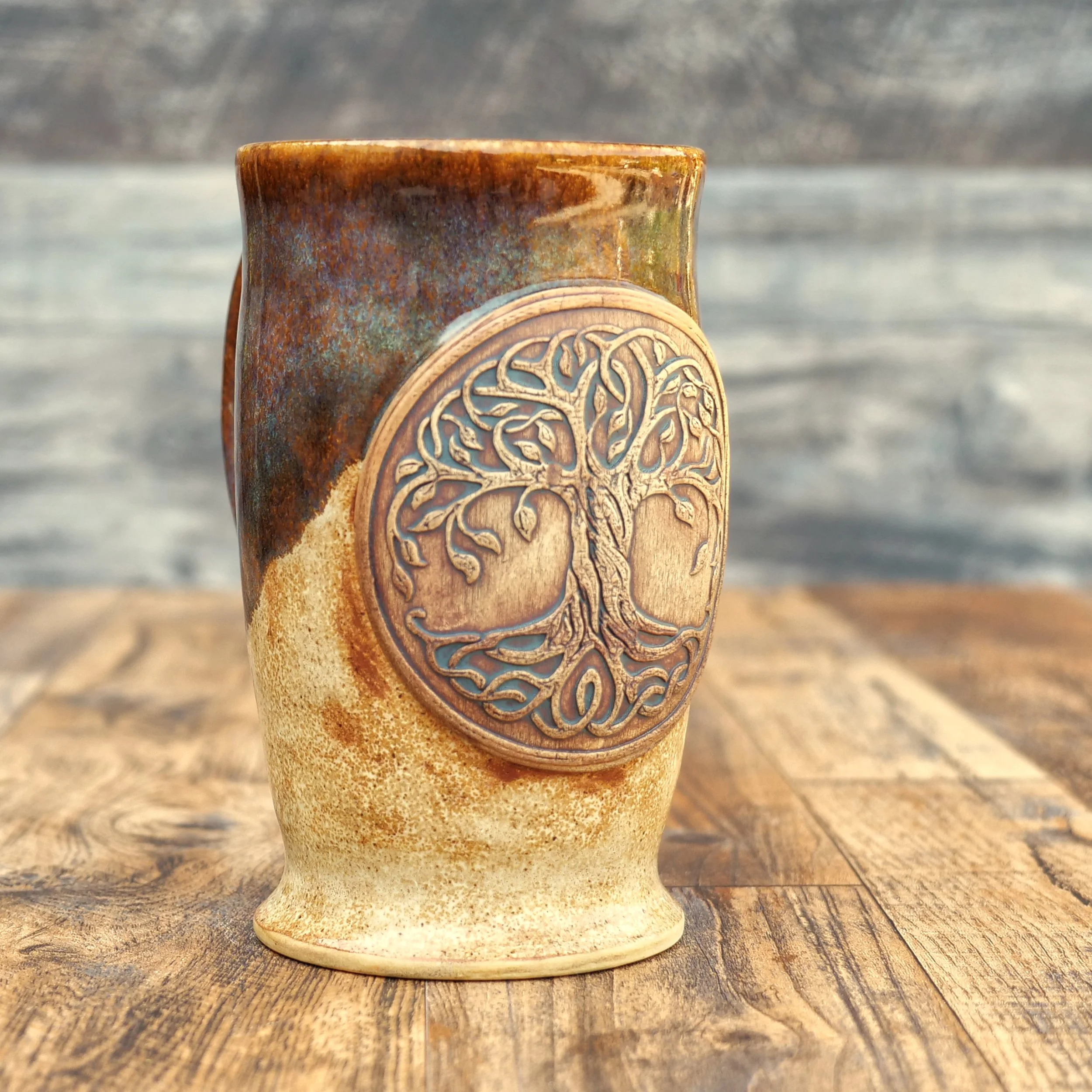 Handmade Tree of Life Mug by Elderkiln Ceramics featuring a sculpted Tree of Life medallion, Celtic-inspired details, and layered earthy stoneware glazes.