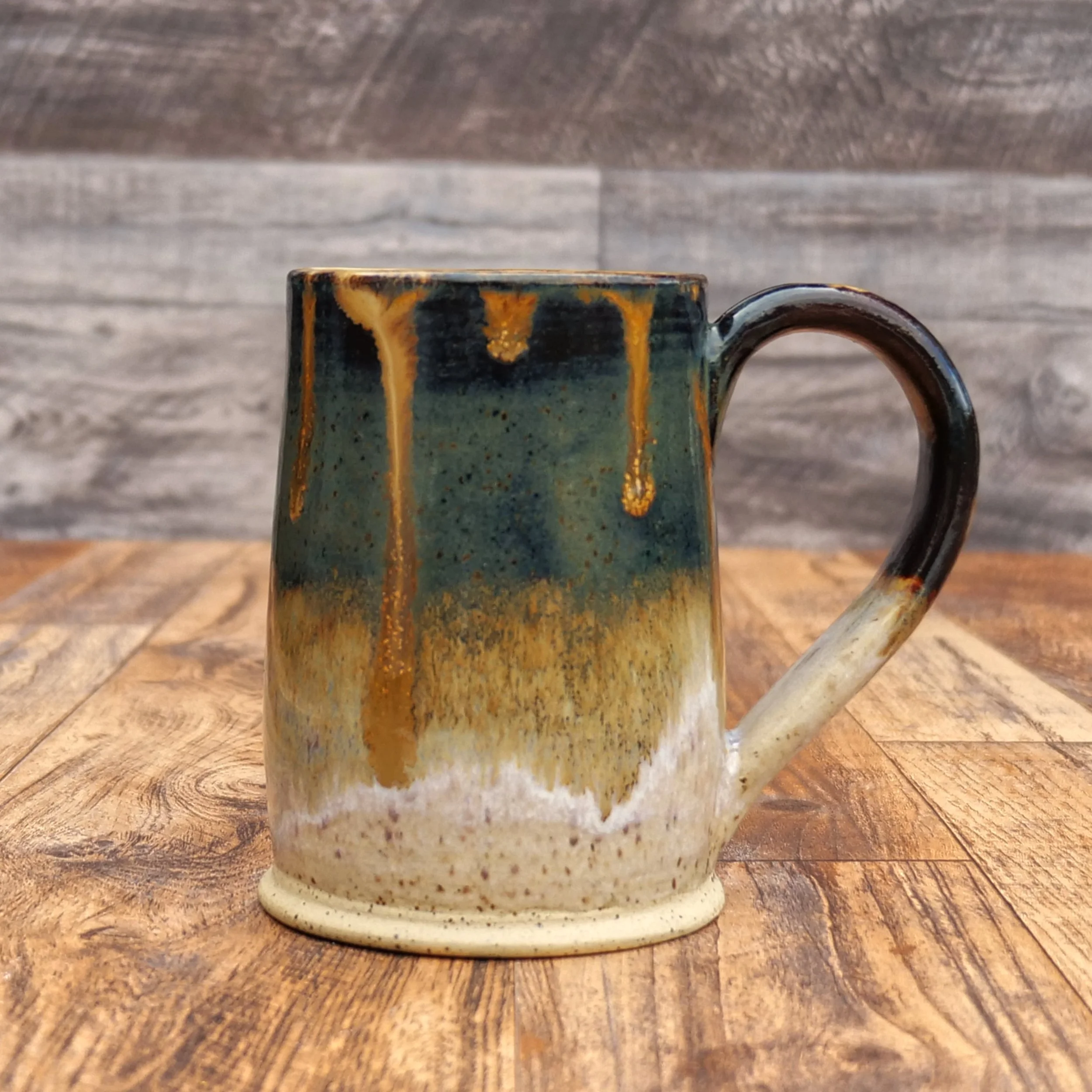 Handmade Amberfall Mug by Elderkiln Ceramics featuring layered amber, bronze, and forest-toned stoneware glazes with flowing natural glaze effects.
