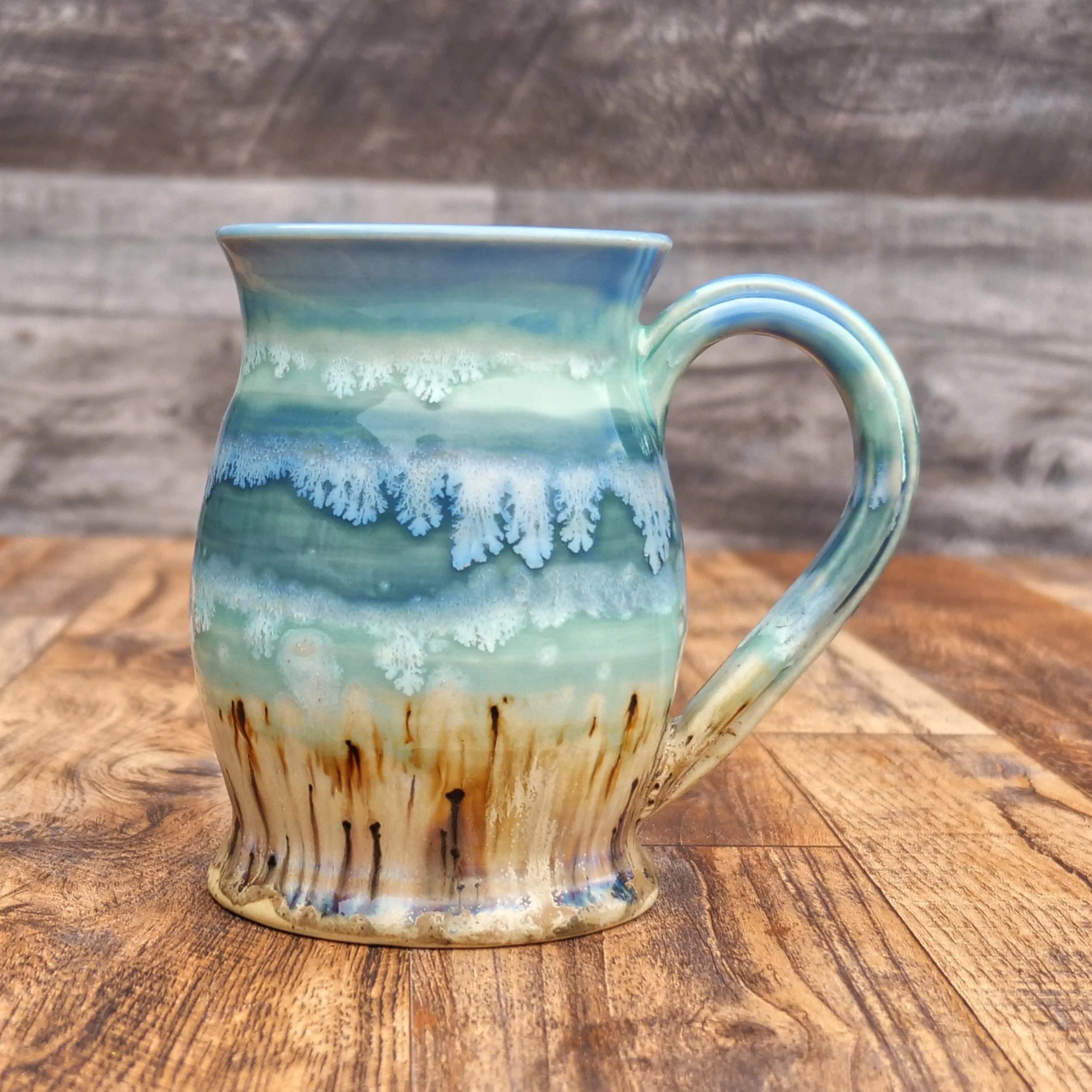 Handmade Tidewater Mug by Elderkiln Ceramics featuring layered coastal blue, seafoam, and sandy stoneware glazes with flowing organic textures.