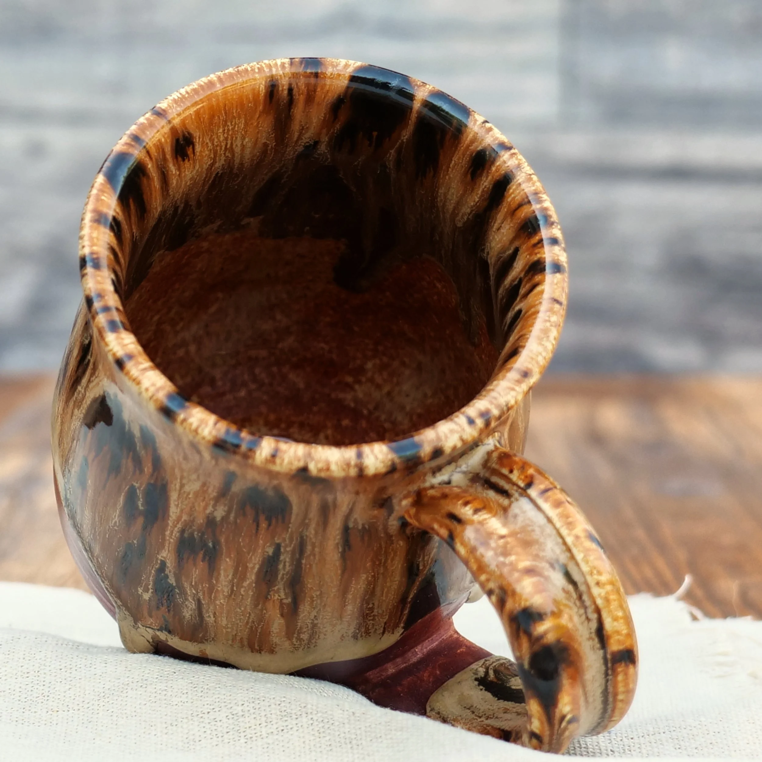 Handmade Emberbark Mug by Elderkiln Ceramics featuring layered bark-inspired glazes, flowing earthy tones, and a warm iron-red stoneware base.