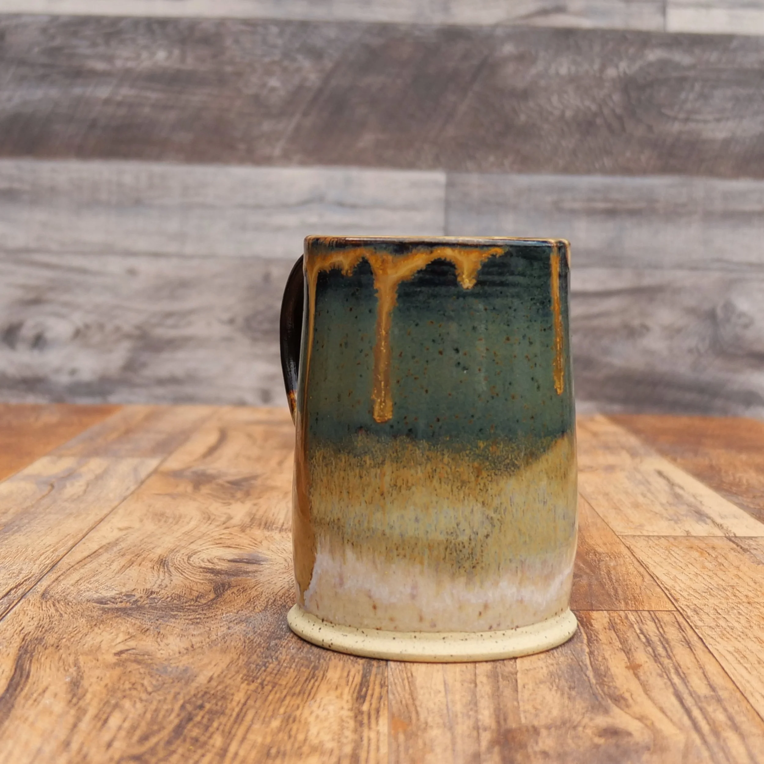 Handmade Amberfall Mug by Elderkiln Ceramics featuring layered amber, bronze, and forest-toned stoneware glazes with flowing natural glaze effects.