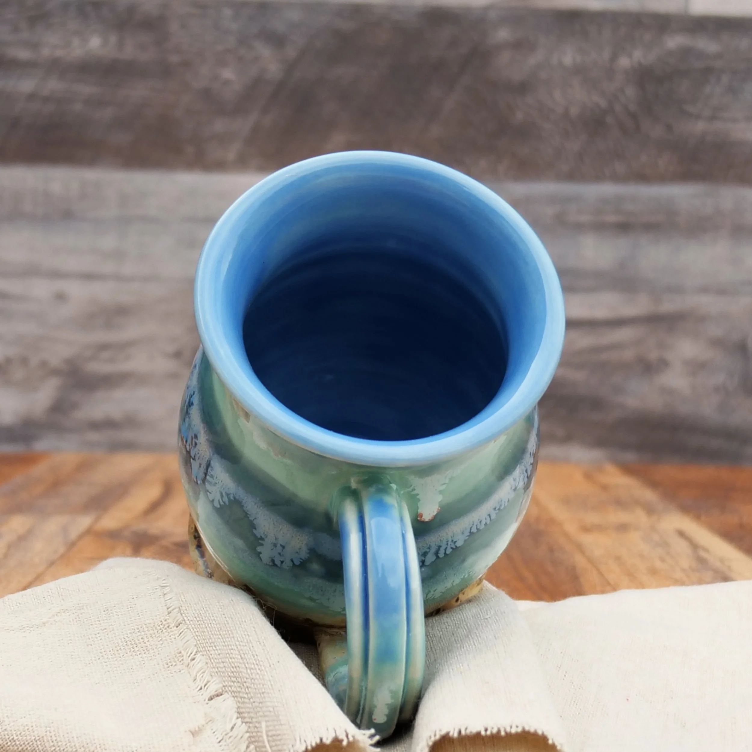Handmade Tidewater Mug by Elderkiln Ceramics featuring layered coastal blue, seafoam, and sandy stoneware glazes with flowing organic textures.