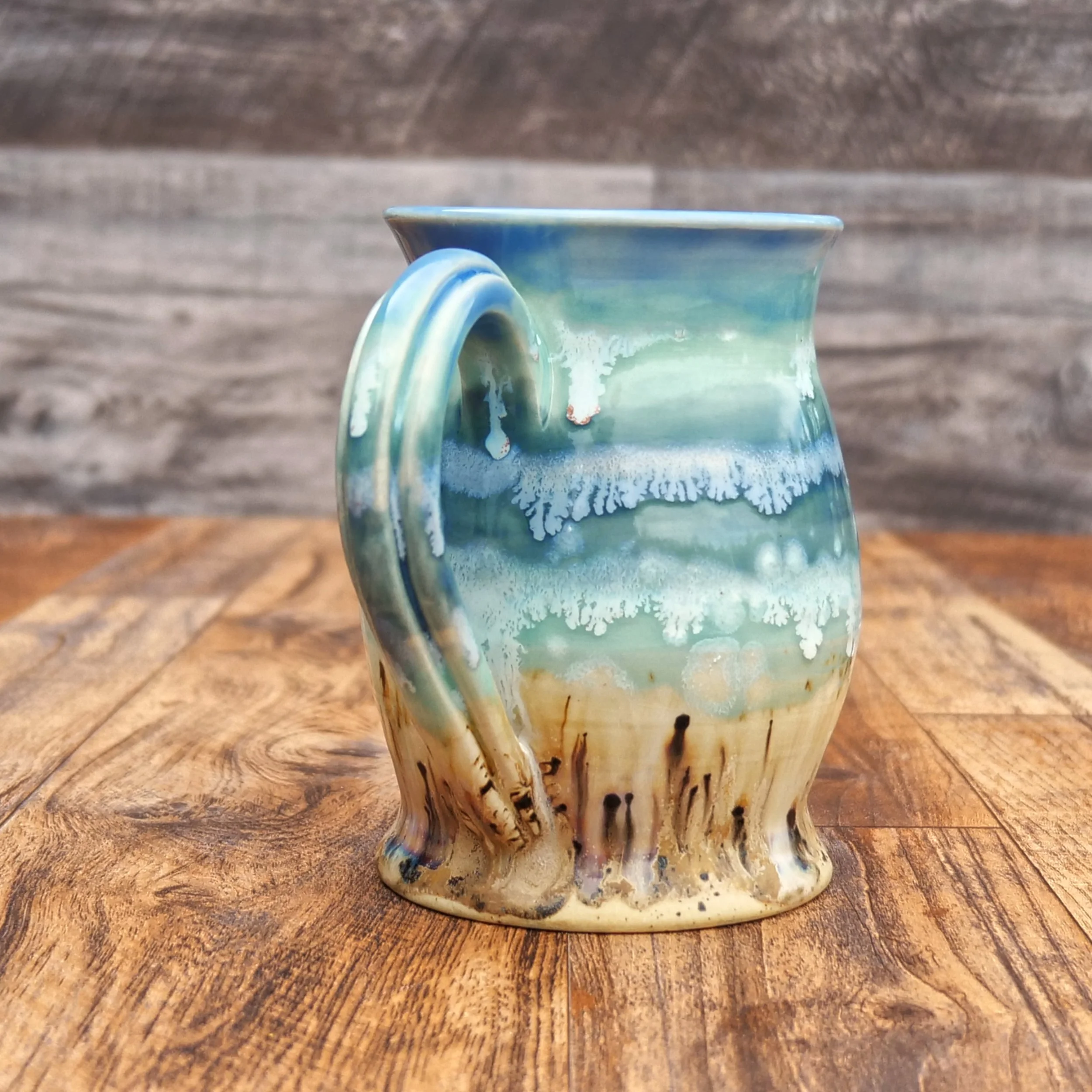 Handmade Tidewater Mug by Elderkiln Ceramics featuring layered coastal blue, seafoam, and sandy stoneware glazes with flowing organic textures.