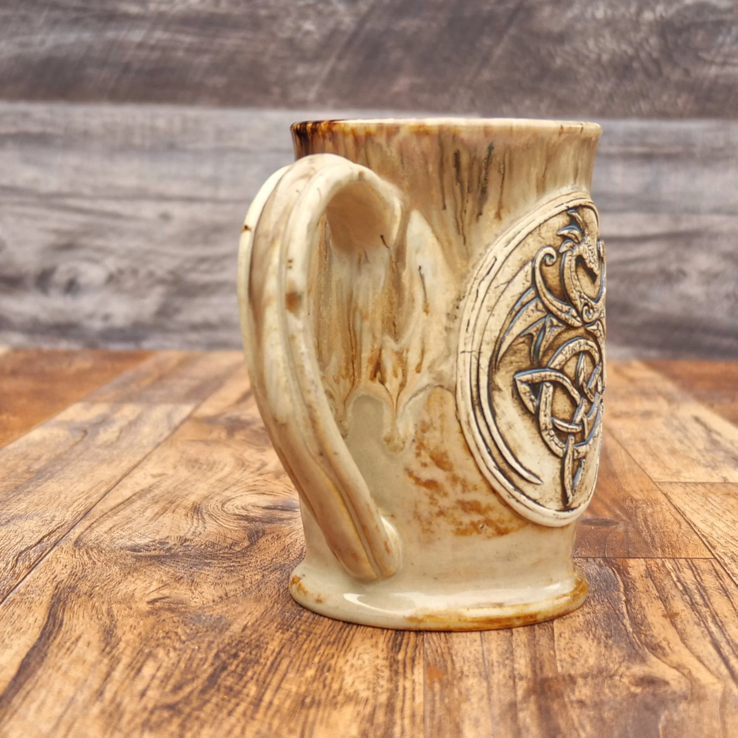 Handmade Celtic Dragon Mug by Elderkiln Ceramics featuring a sculpted dragon and Celtic knot design in warm earthy stoneware glazes.