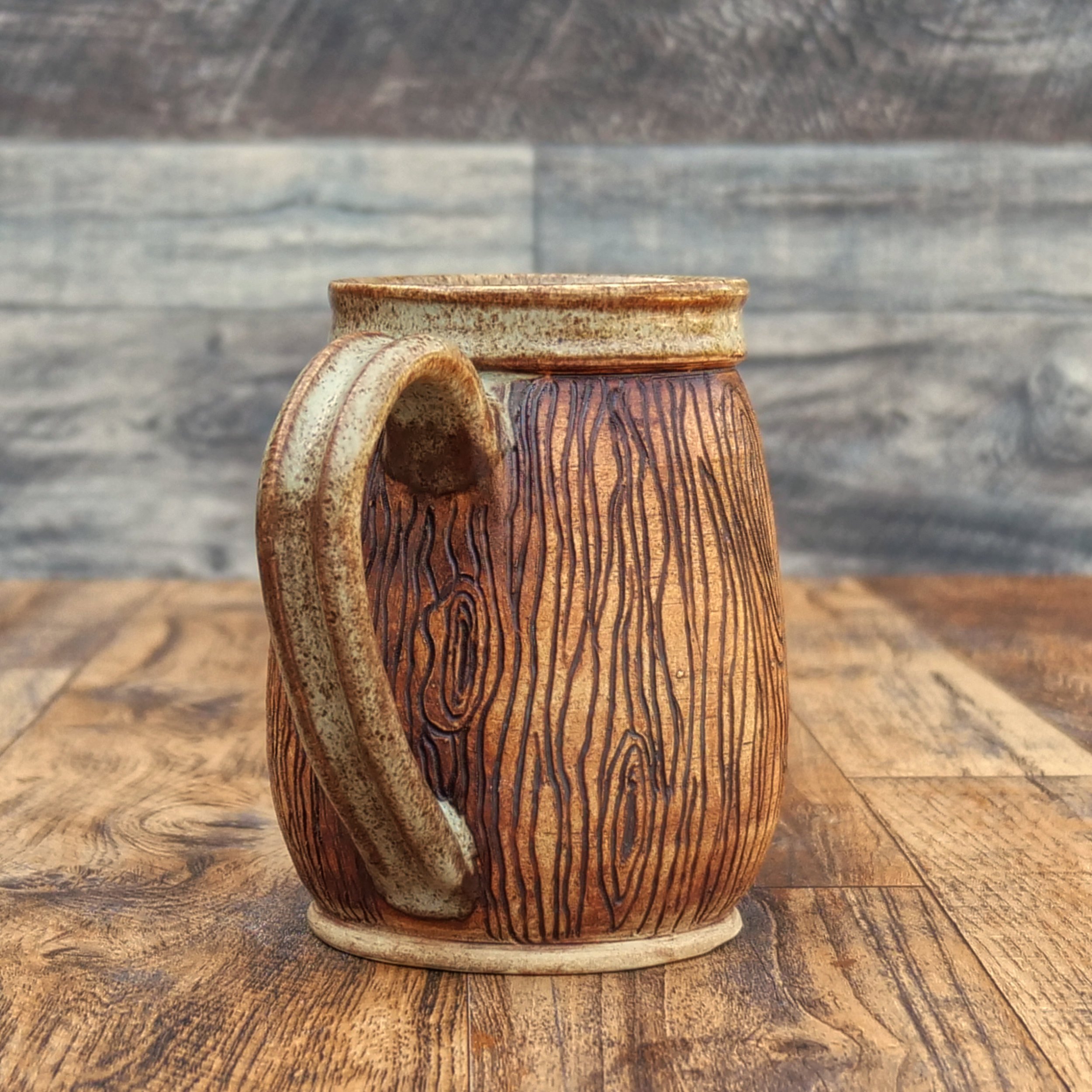 Handmade stoneware Wayfinder Mug by Elderkiln Ceramics featuring a raised Vegvísir symbol, hand-carved woodgrain texture, and warm earth-tone glazes.