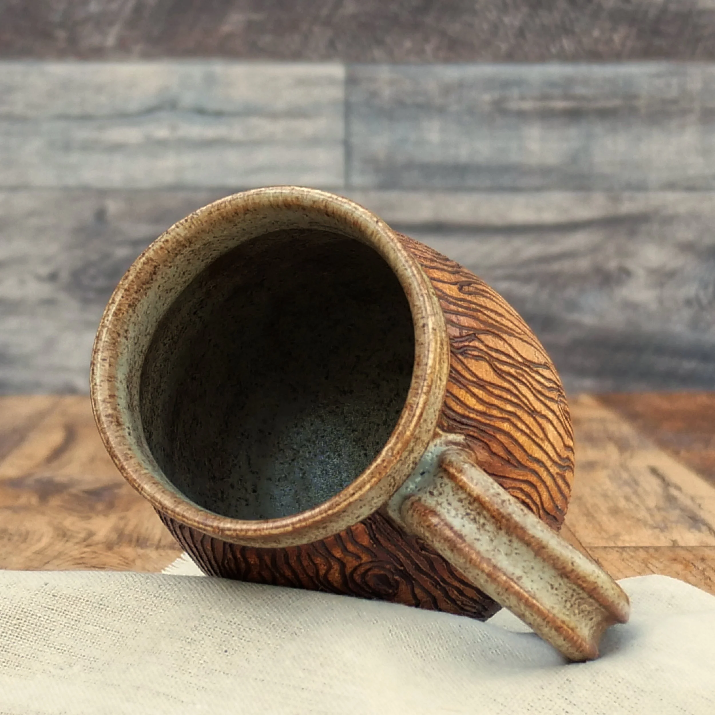 Handmade stoneware Wayfinder Mug by Elderkiln Ceramics featuring a raised Vegvísir symbol, hand-carved woodgrain texture, and warm earth-tone glazes.
