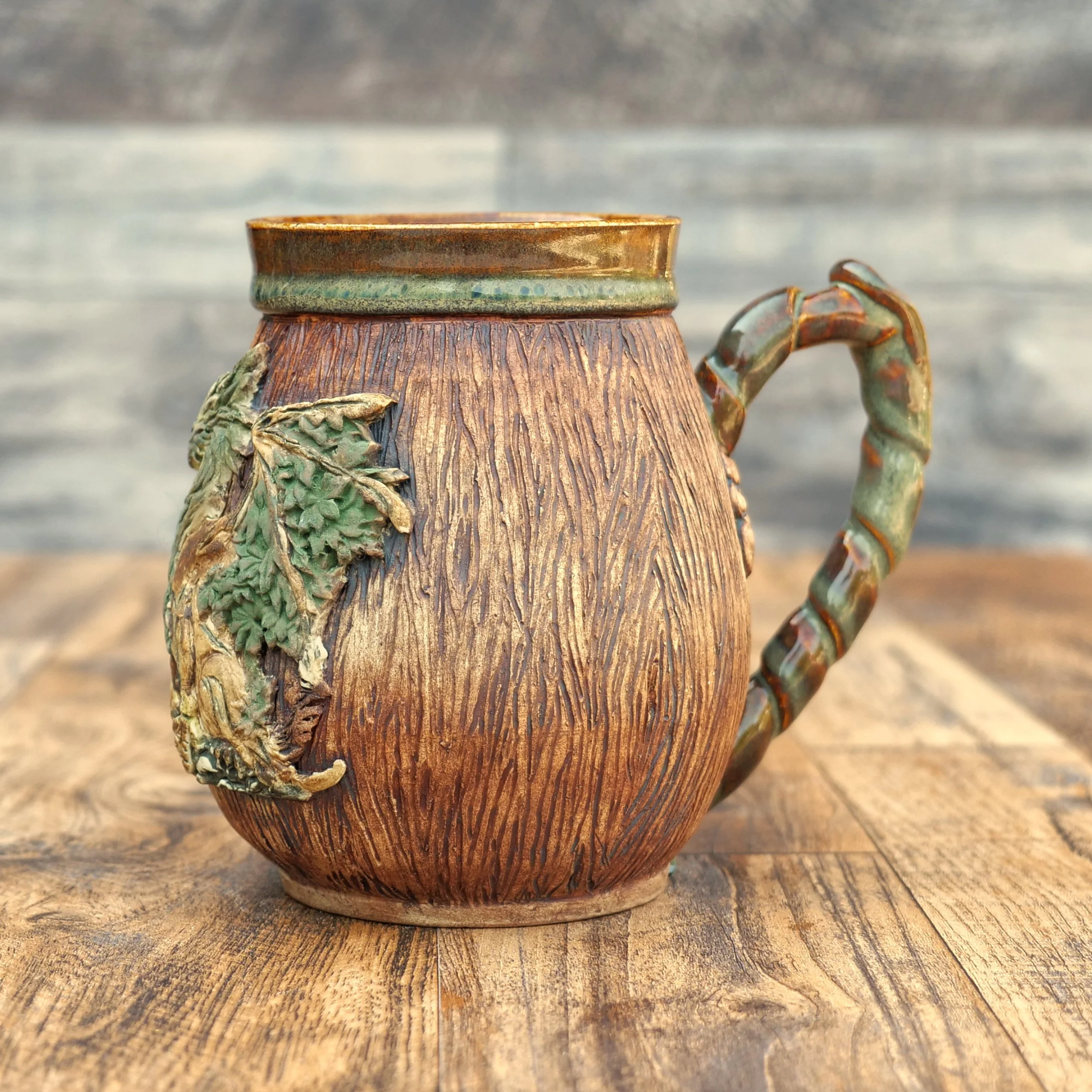 Handmade Woodland Dragon Mug by Elderkiln Ceramics featuring a sculpted forest dragon, carved woodgrain texture, branch-style handle, and earthy woodland glazes.