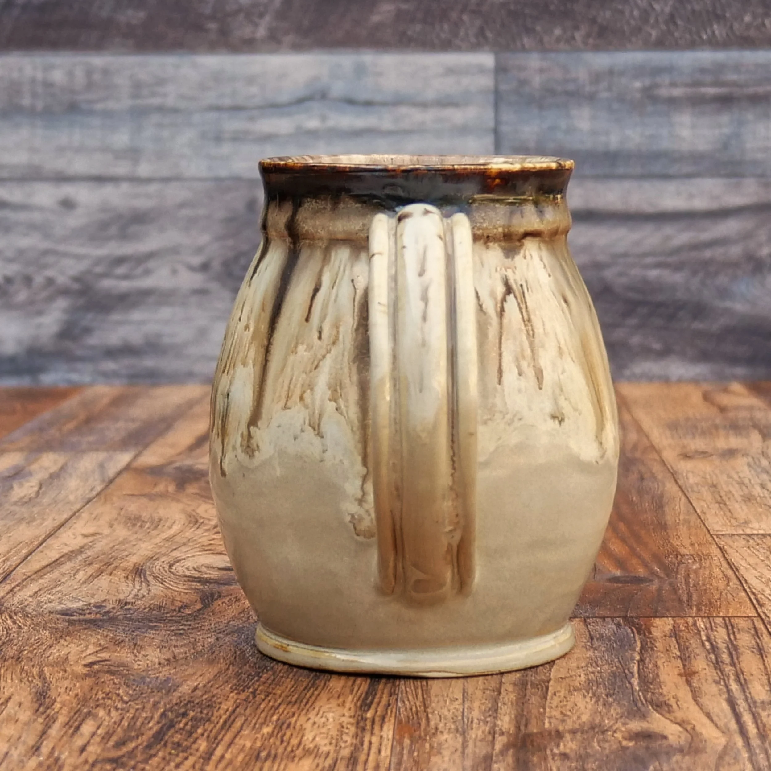 Handmade Wayfinder Mug by Elderkiln Ceramics featuring a sculpted Vegvísir symbol and layered earthy stoneware glazes in cream, amber, and brown tones.