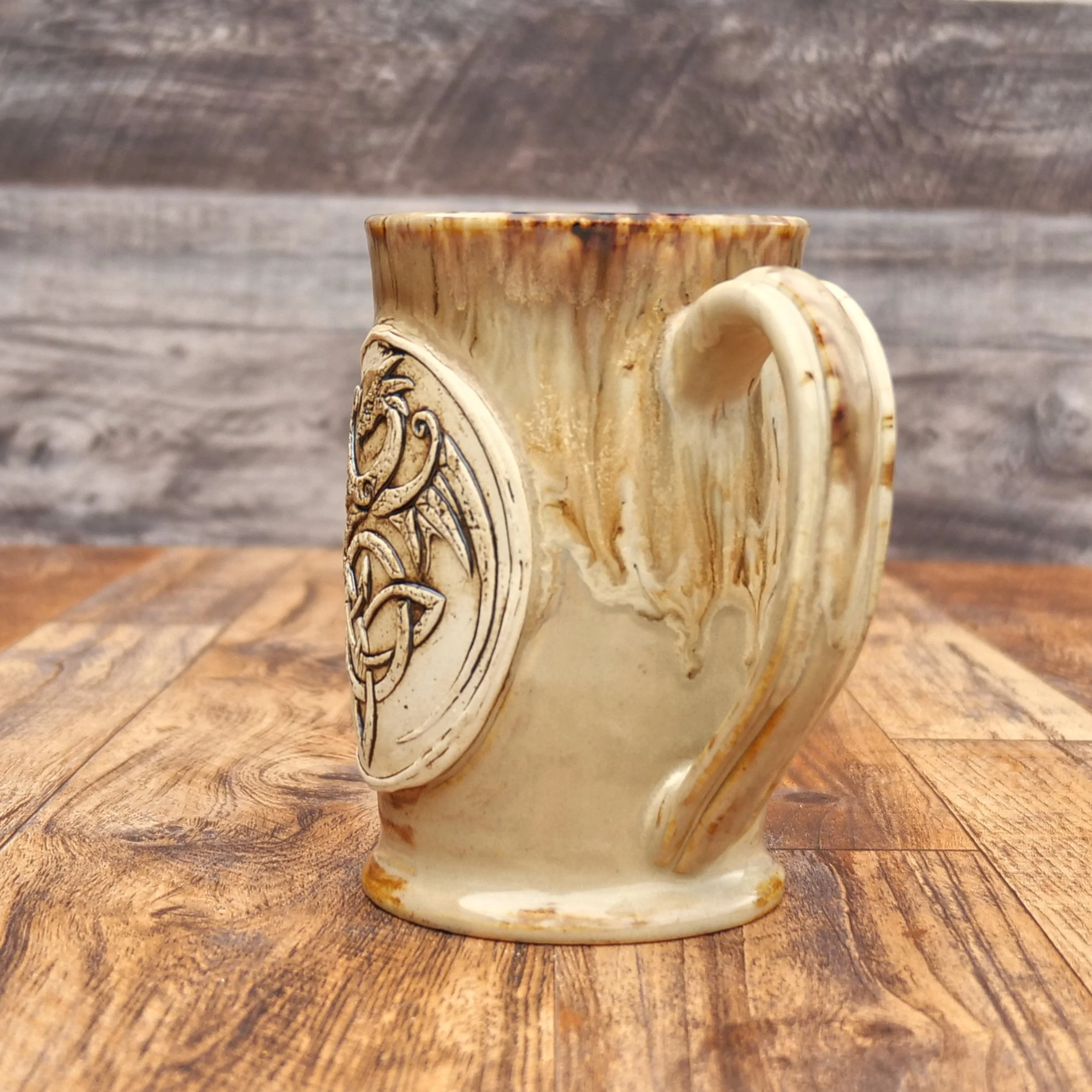 Handmade Celtic Dragon Mug by Elderkiln Ceramics featuring a sculpted dragon and Celtic knot design in warm earthy stoneware glazes.