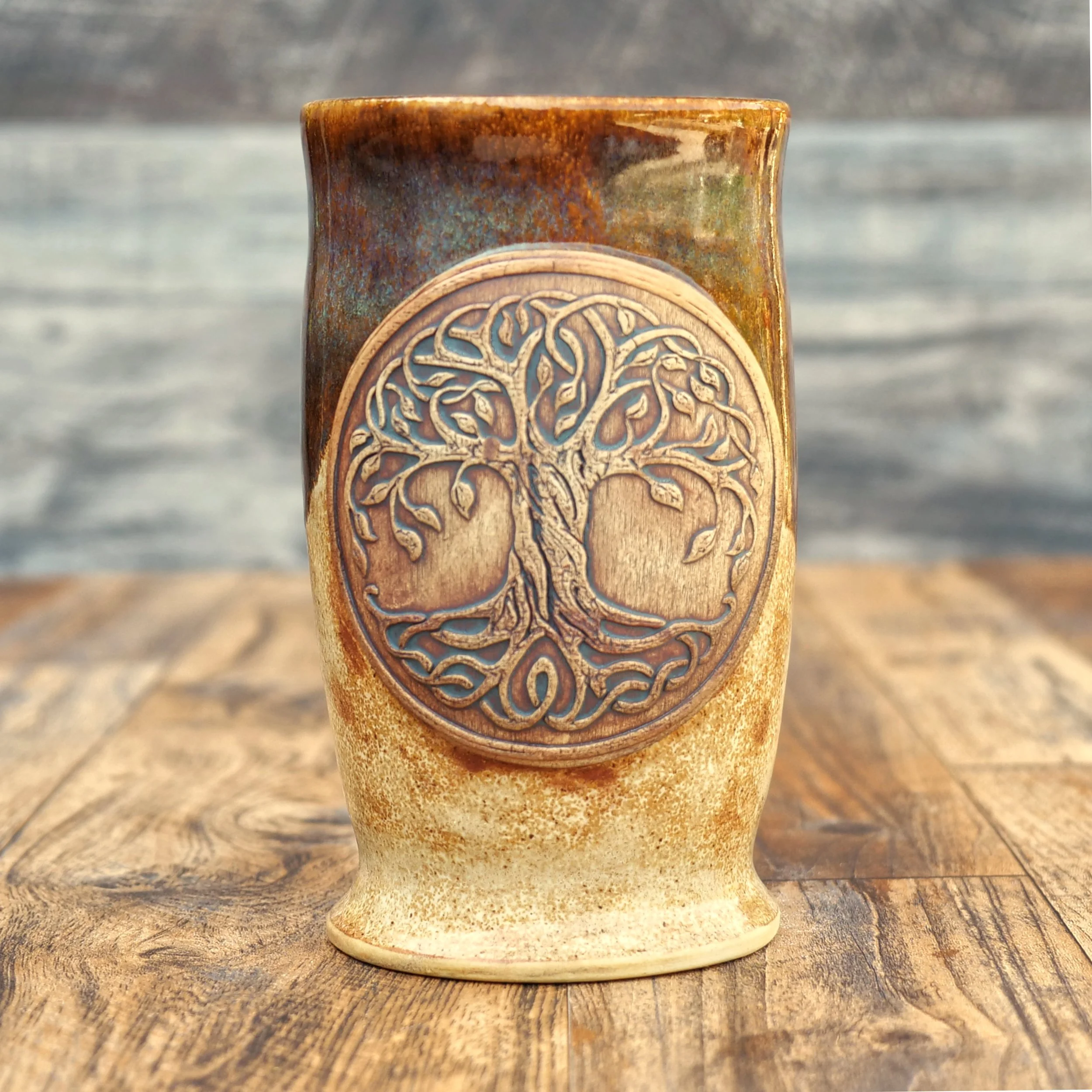 Handmade Tree of Life Mug by Elderkiln Ceramics featuring a sculpted Tree of Life medallion, Celtic-inspired details, and layered earthy stoneware glazes.