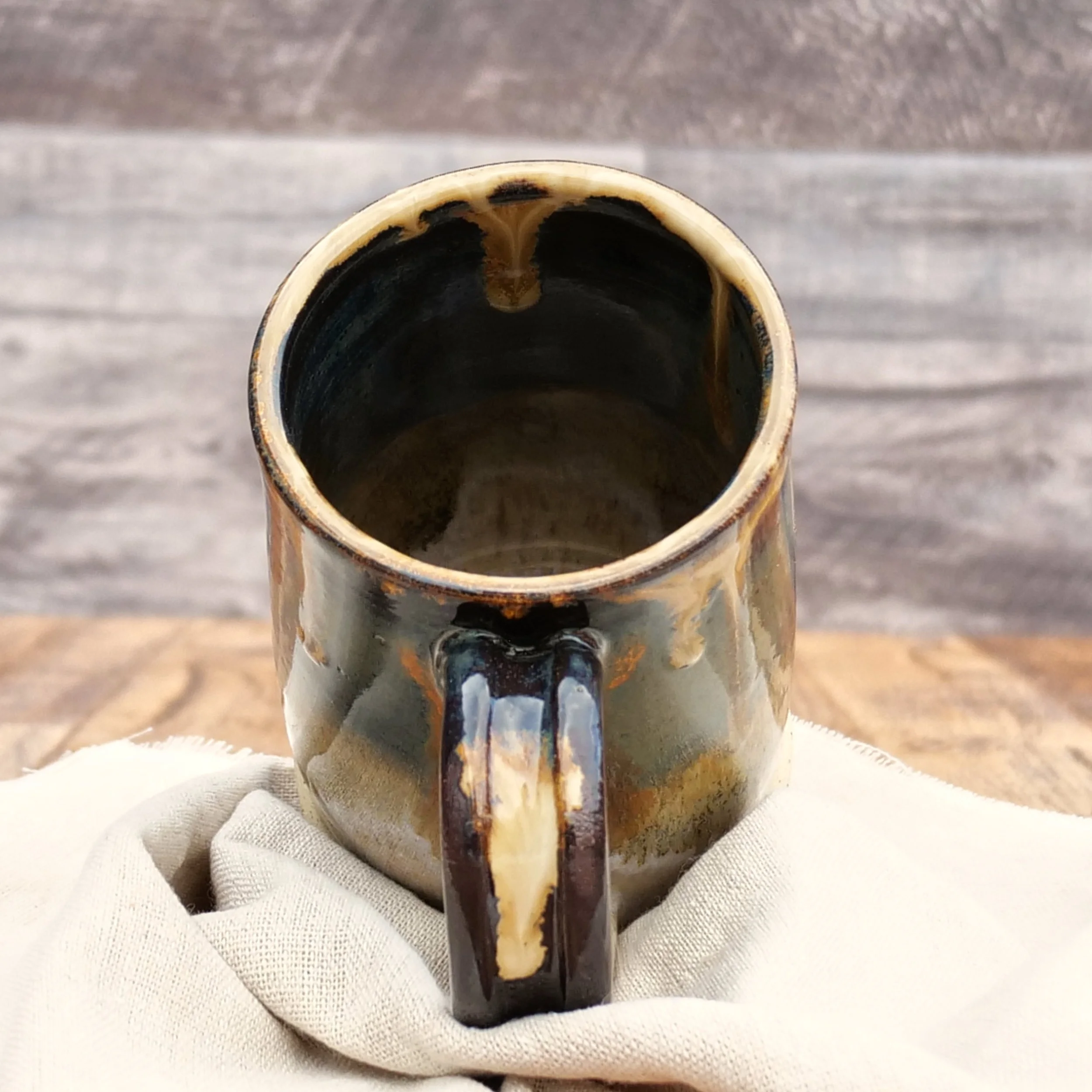 Handmade Amberfall Mug by Elderkiln Ceramics featuring layered amber, bronze, and forest-toned stoneware glazes with flowing natural glaze effects.