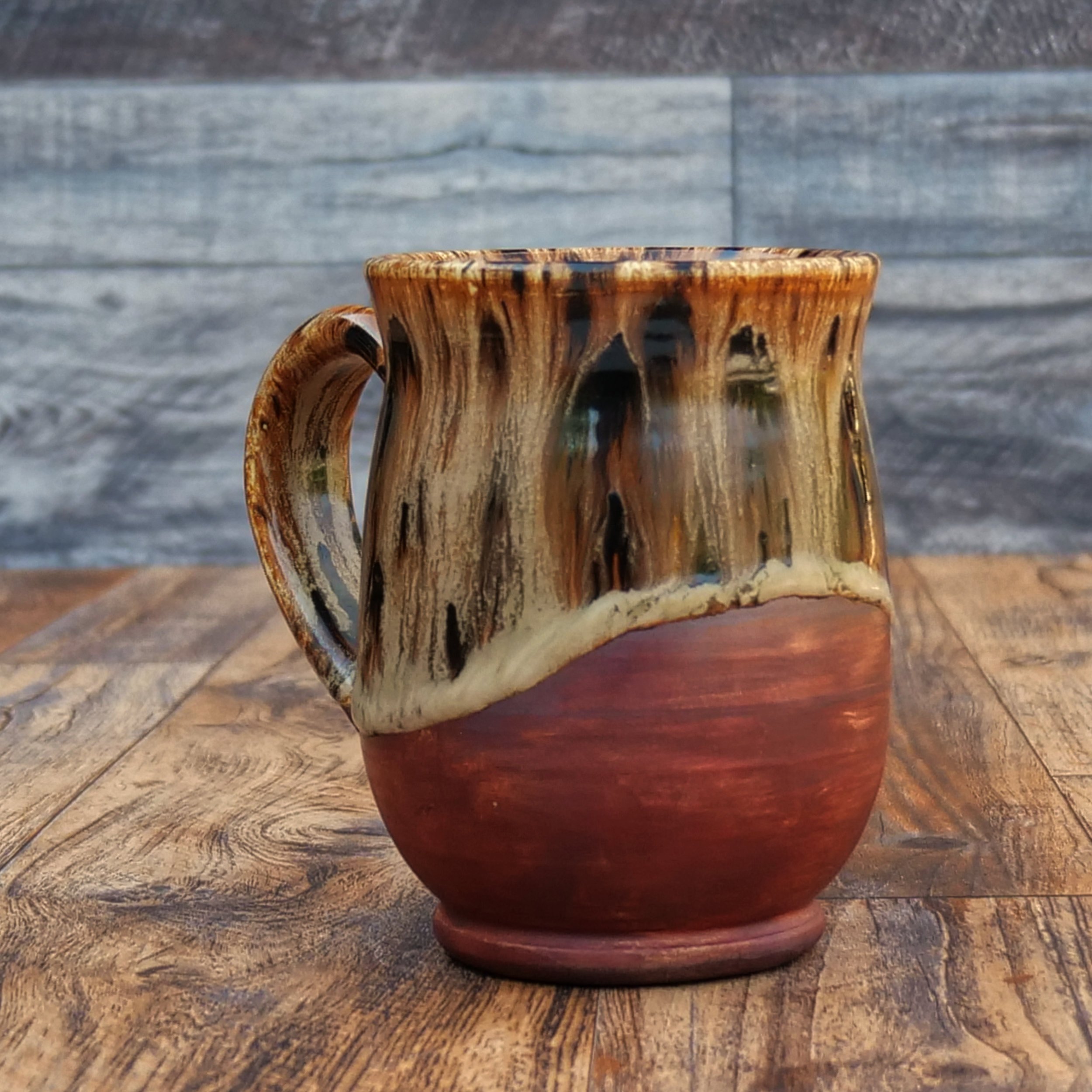 Handmade Emberbark Mug by Elderkiln Ceramics featuring layered bark-inspired glazes, flowing earthy tones, and a warm iron-red stoneware base.