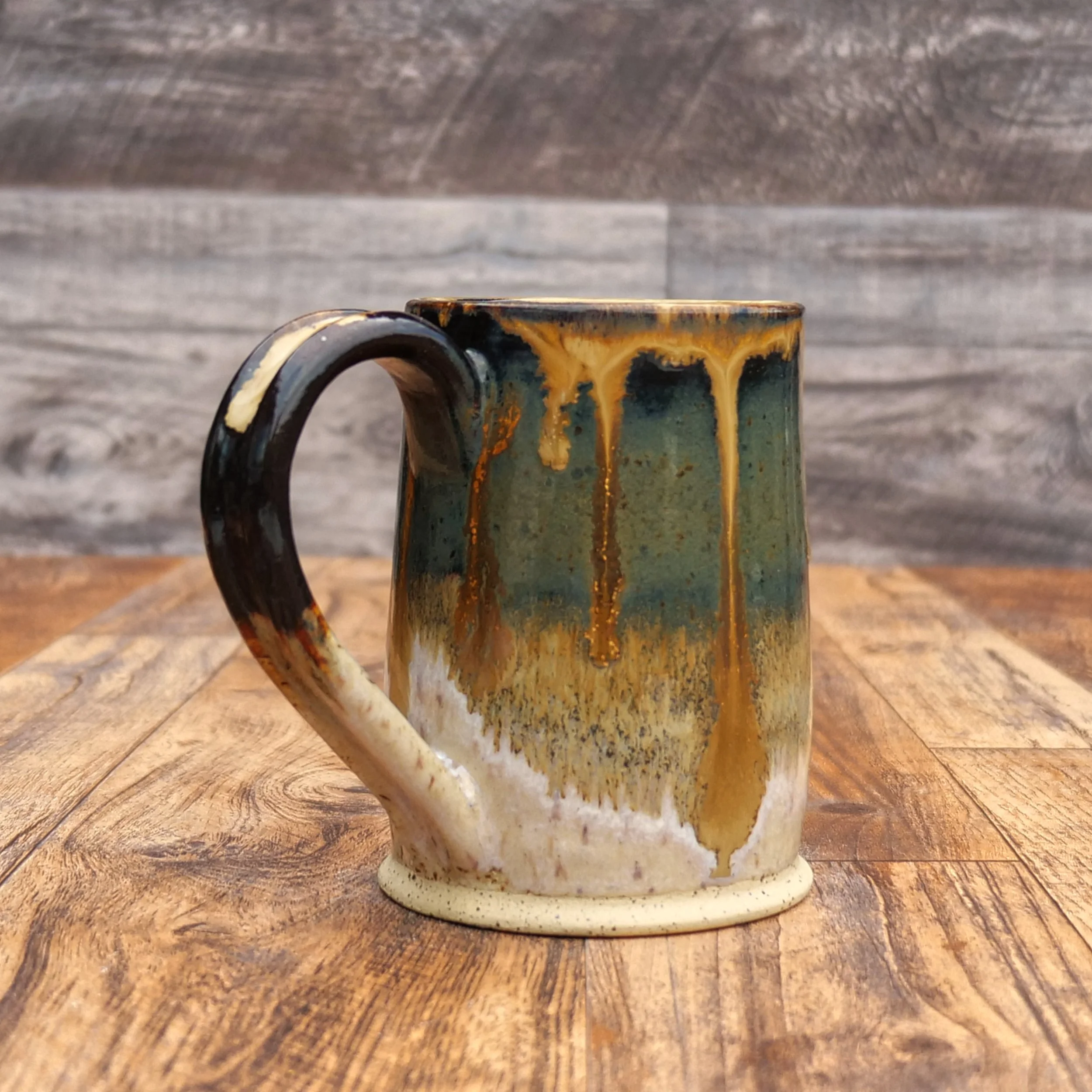 Handmade Amberfall Mug by Elderkiln Ceramics featuring layered amber, bronze, and forest-toned stoneware glazes with flowing natural glaze effects.