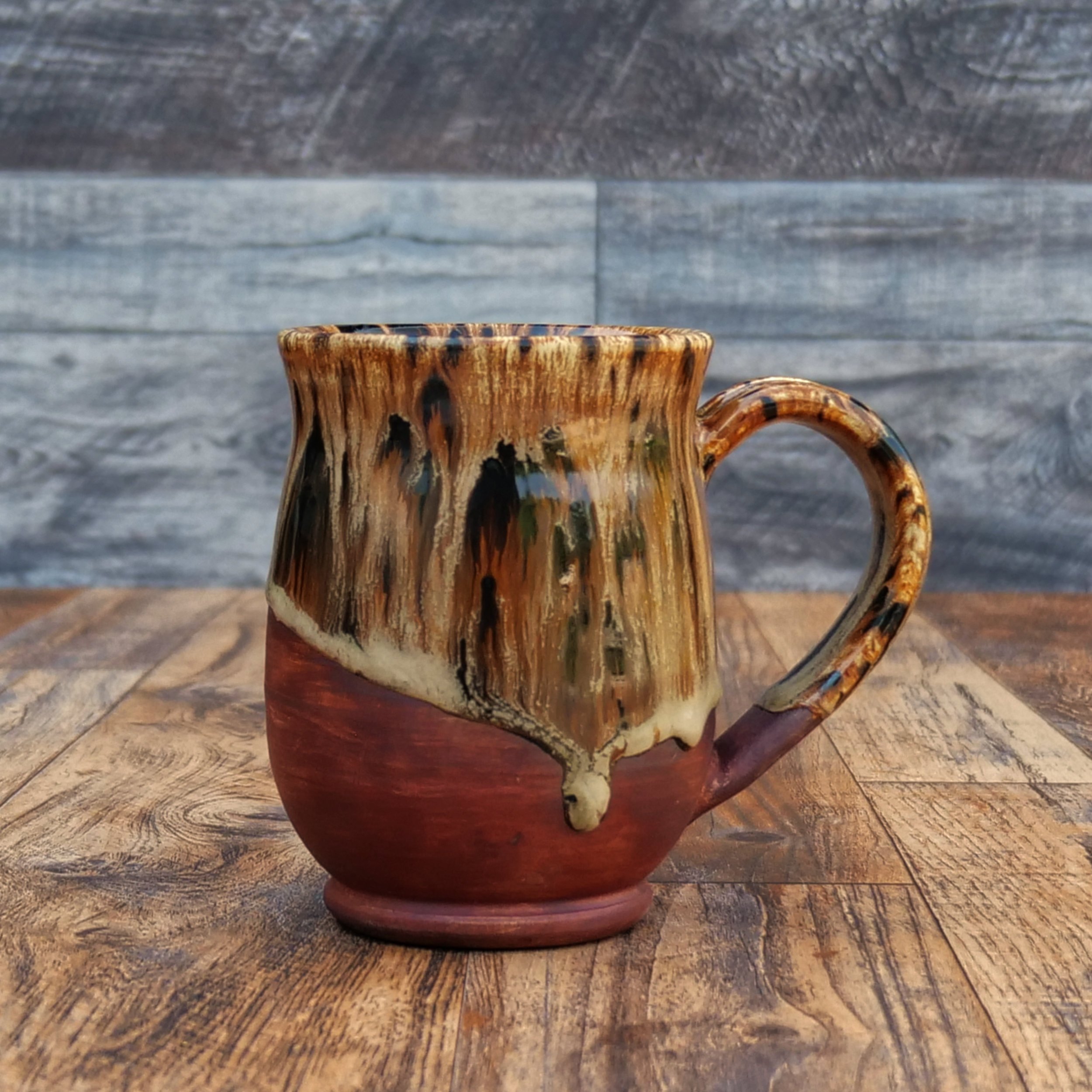 Handmade Emberbark Mug by Elderkiln Ceramics featuring layered bark-inspired glazes, flowing earthy tones, and a warm iron-red stoneware base.