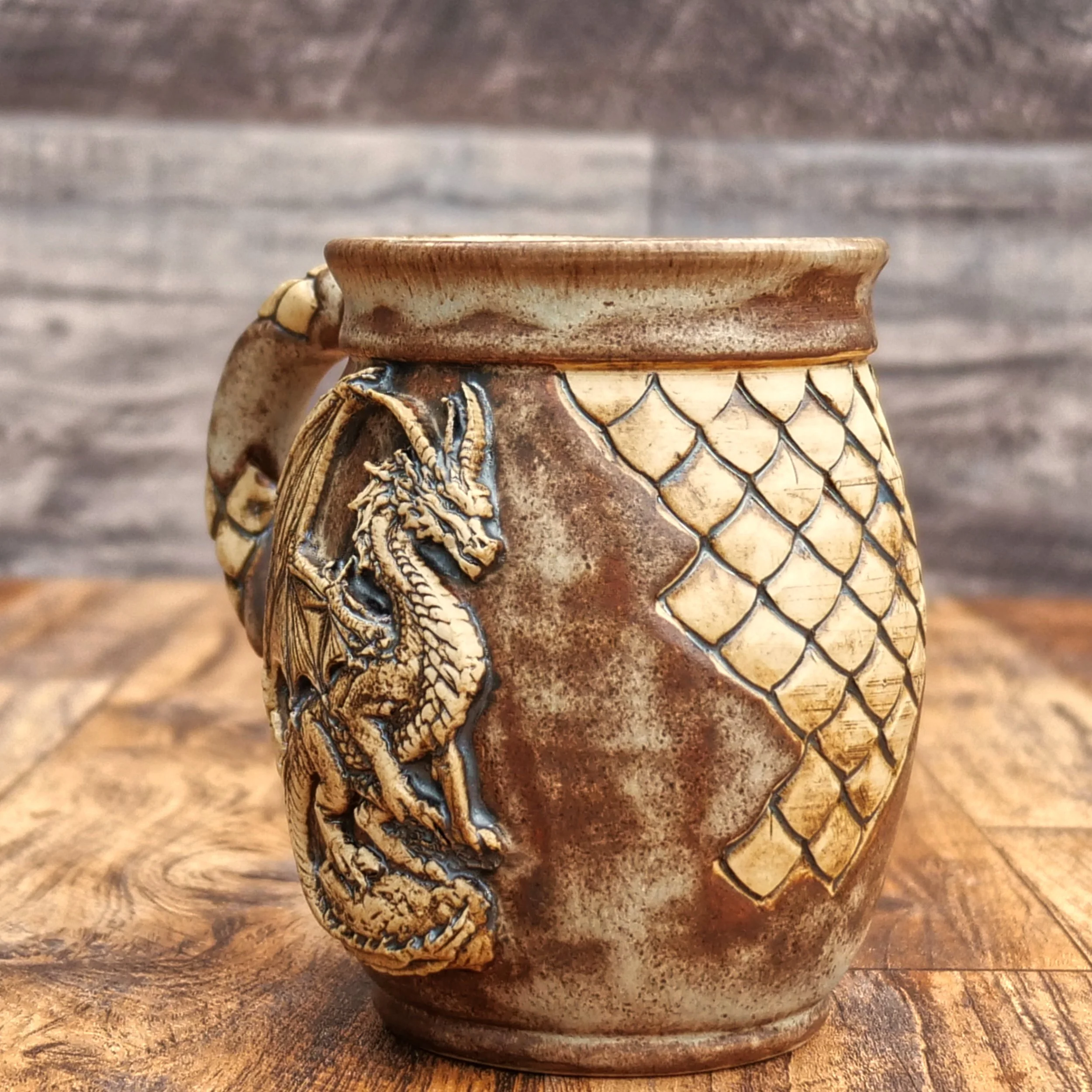 Handmade Dragonstone Mug by Elderkiln Ceramics featuring a sculpted dragon design, individually hand-carved scales, textured handle, and layered earthy brown stoneware glazes.