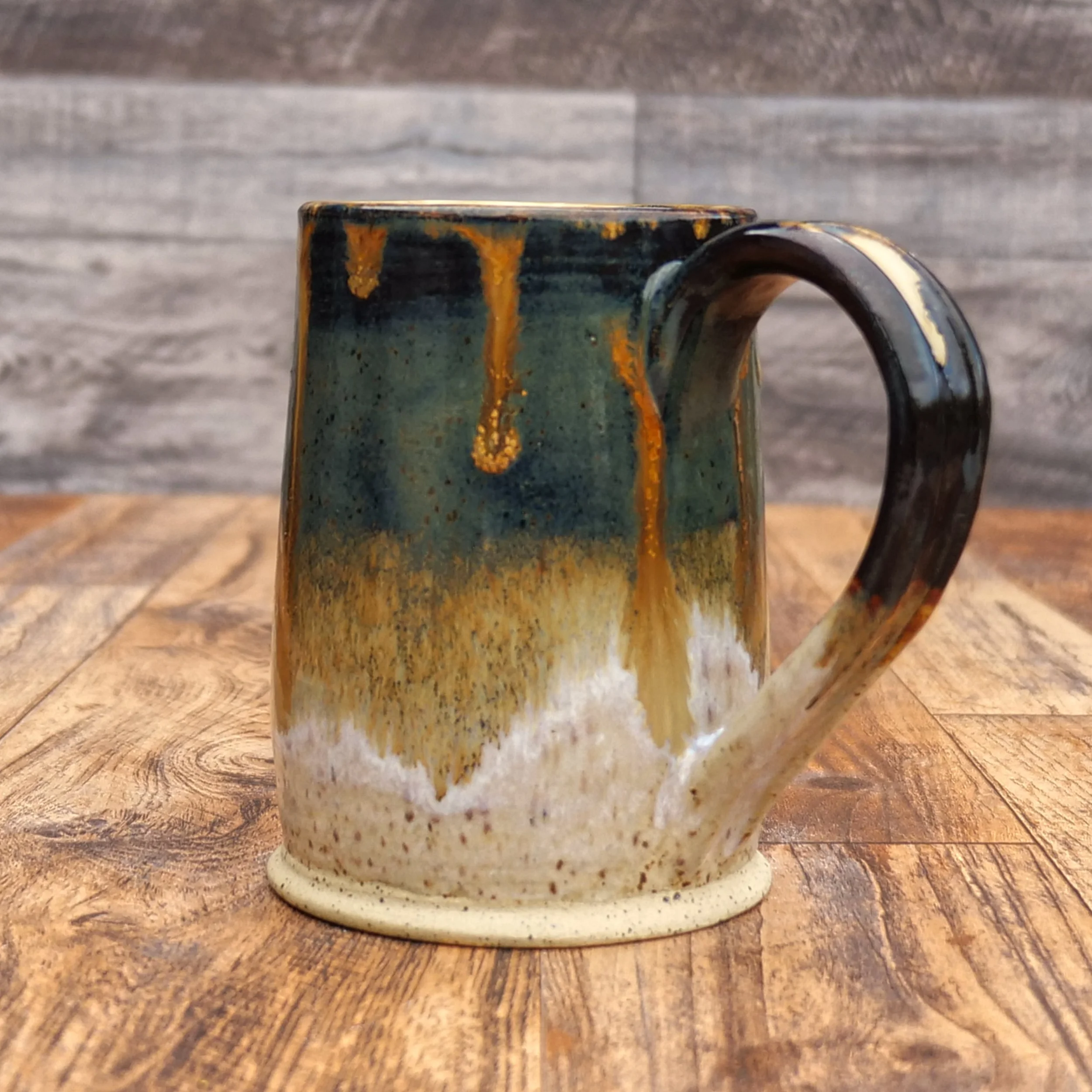 Handmade Amberfall Mug by Elderkiln Ceramics featuring layered amber, bronze, and forest-toned stoneware glazes with flowing natural glaze effects.