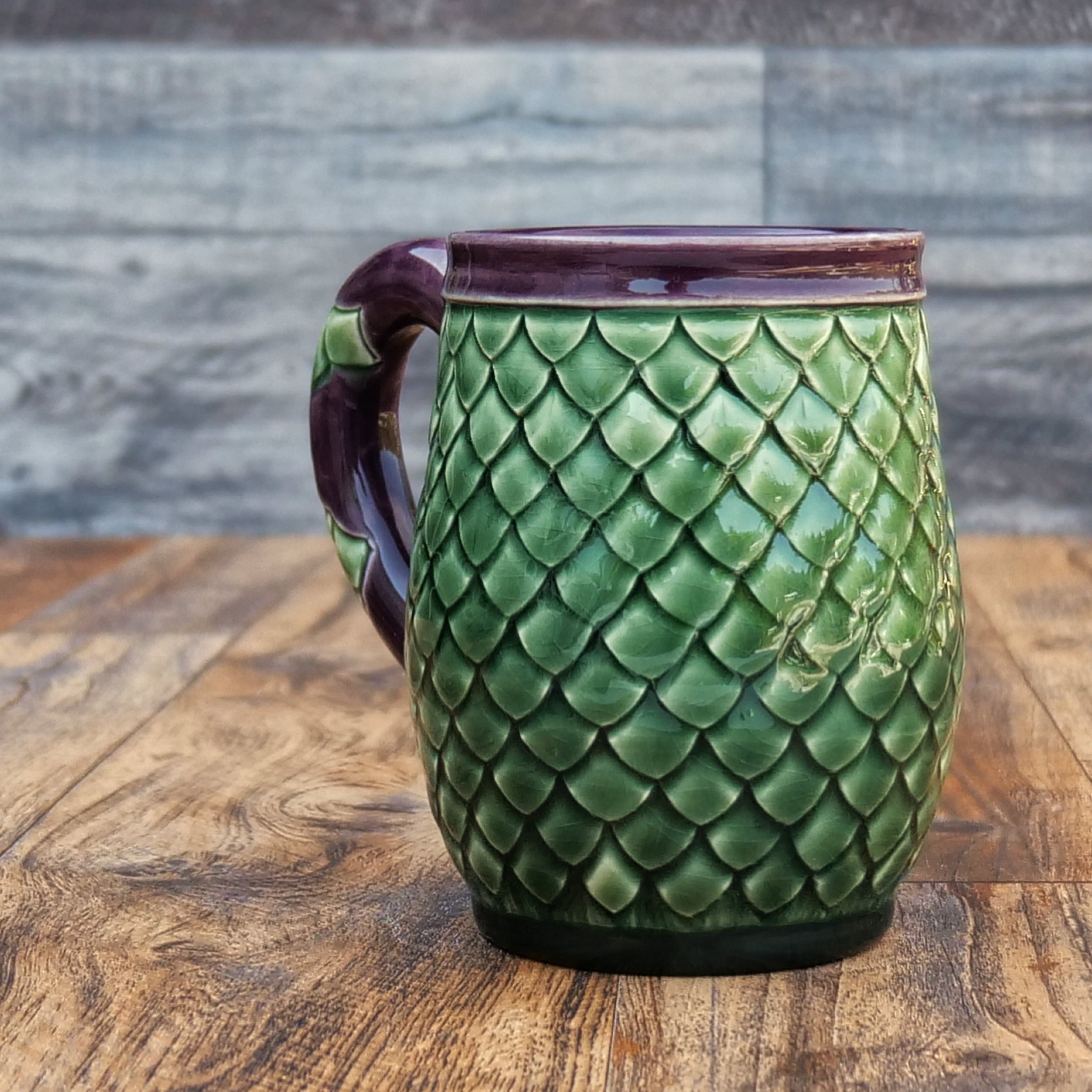 Handmade Emerald Dragon Egg Mug by Elderkiln Ceramics featuring individually sculpted dragon scales and layered emerald green and deep amethyst stoneware glazes.