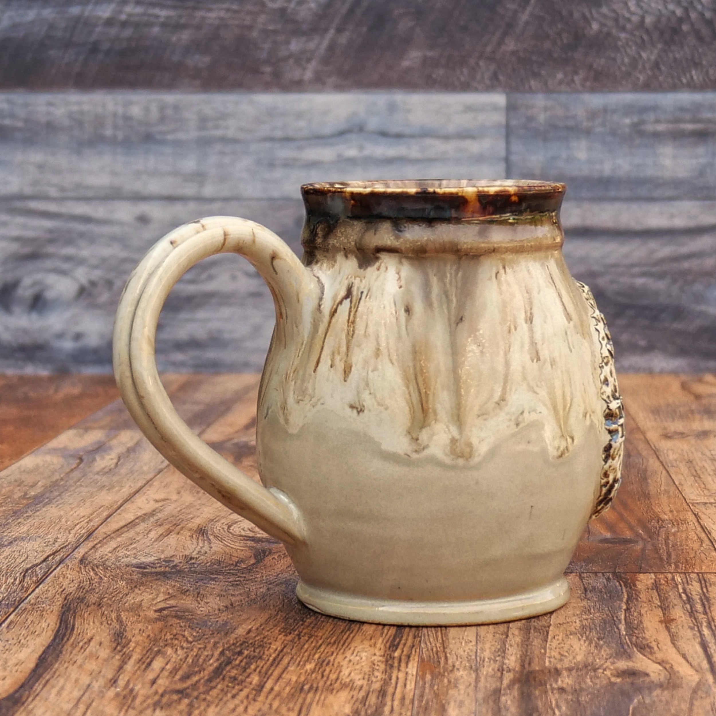 Handmade Wayfinder Mug by Elderkiln Ceramics featuring a sculpted Vegvísir symbol and layered earthy stoneware glazes in cream, amber, and brown tones.