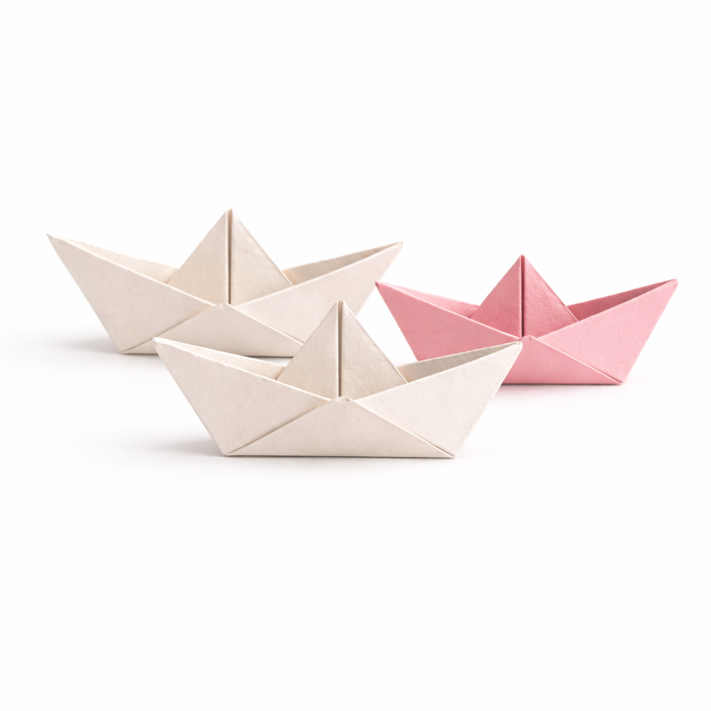 Three paper origami boats, two in white and one in pink, arranged on a white background.