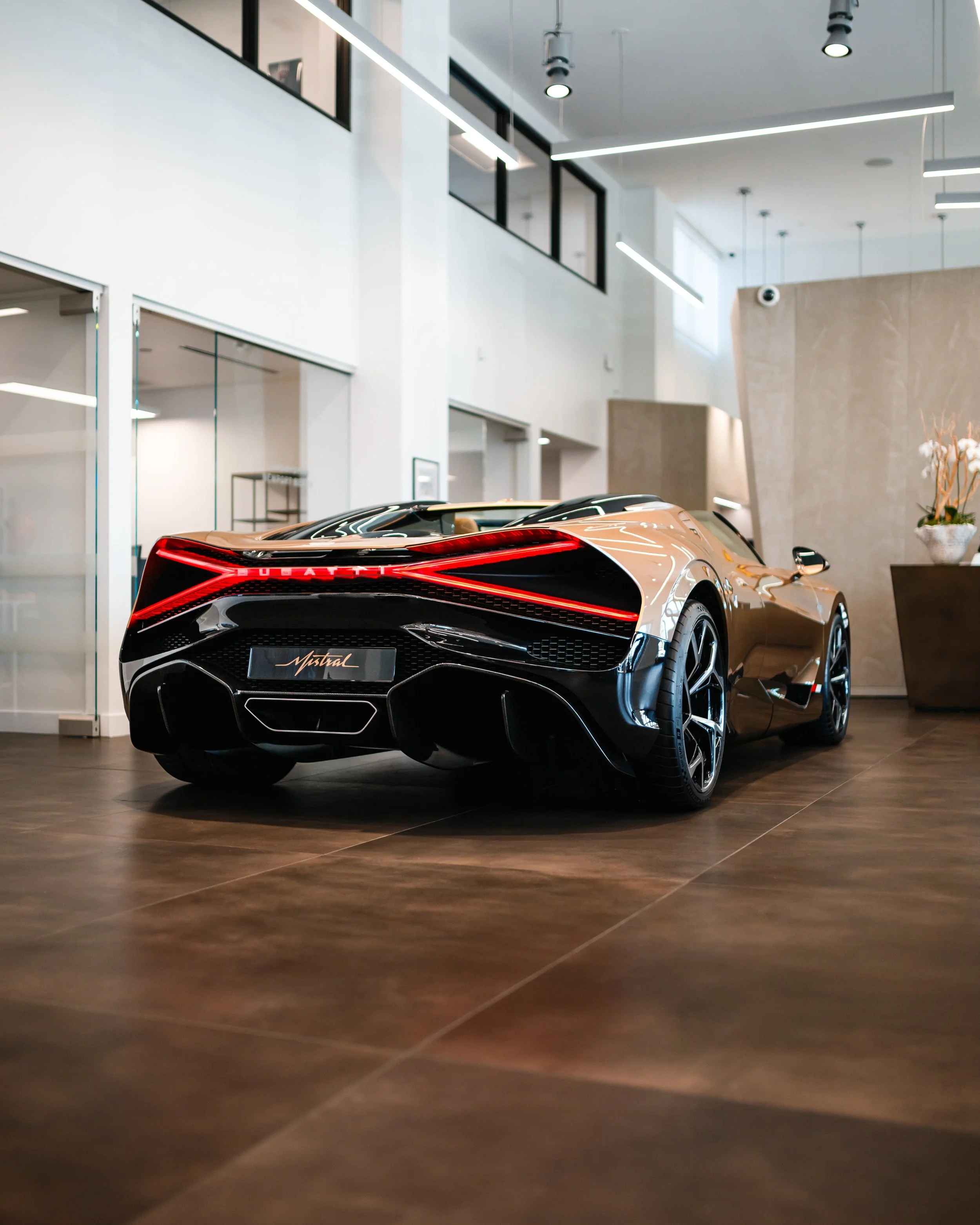 A Bugatti Mistral displayed indoors, showcasing a sleek black and bronze exterior with modern design.