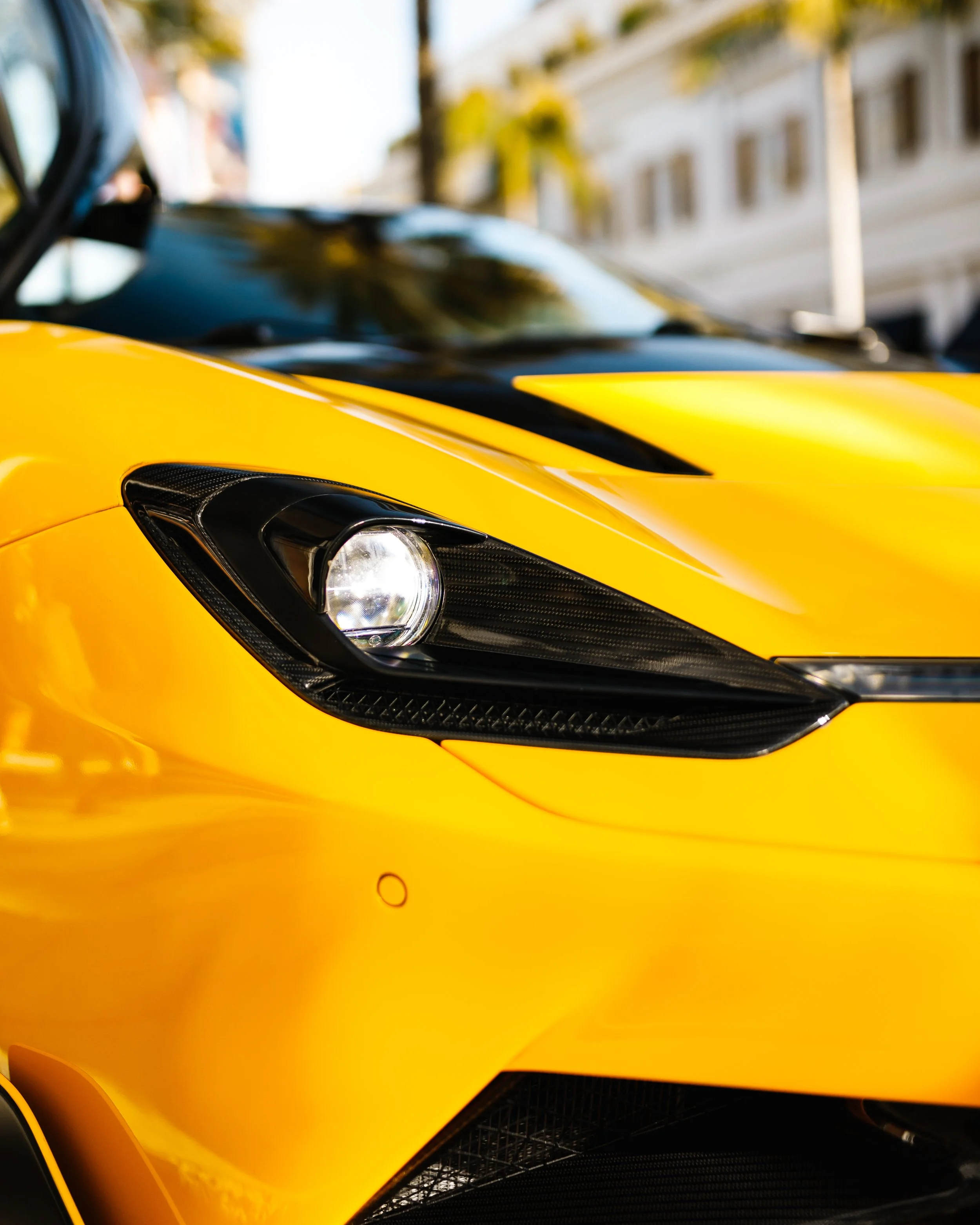 Close-up of the front left side of a Pininfarina Battista, showing the headlight, part of the hood, and side mirror.