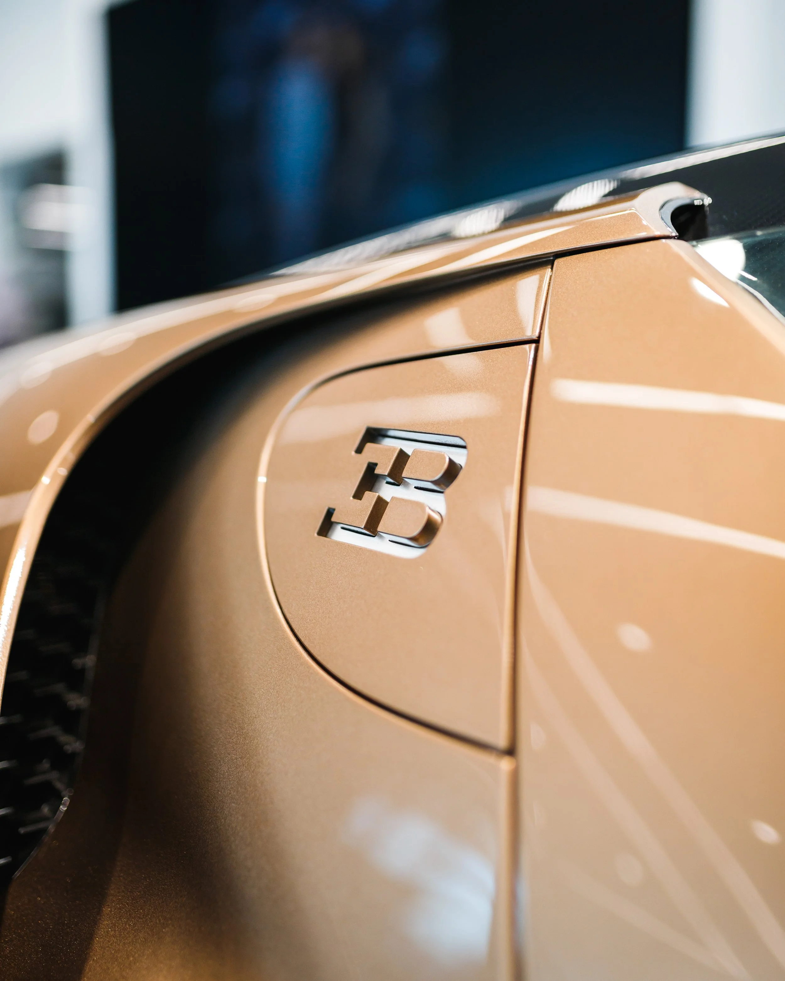 Close-up of a metallic gold Bugatti Mistral with a focus on the 'EB' badge on its side.