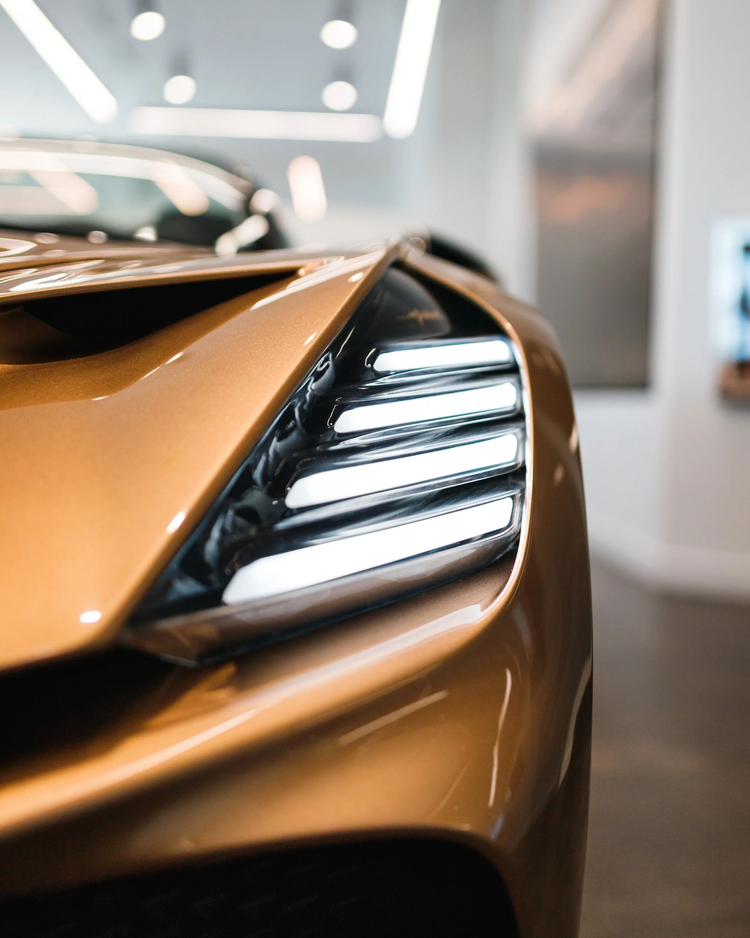 Close-up of a bronze Bugatti Mistral's front corner with distinctive headlight design and sleek curves.