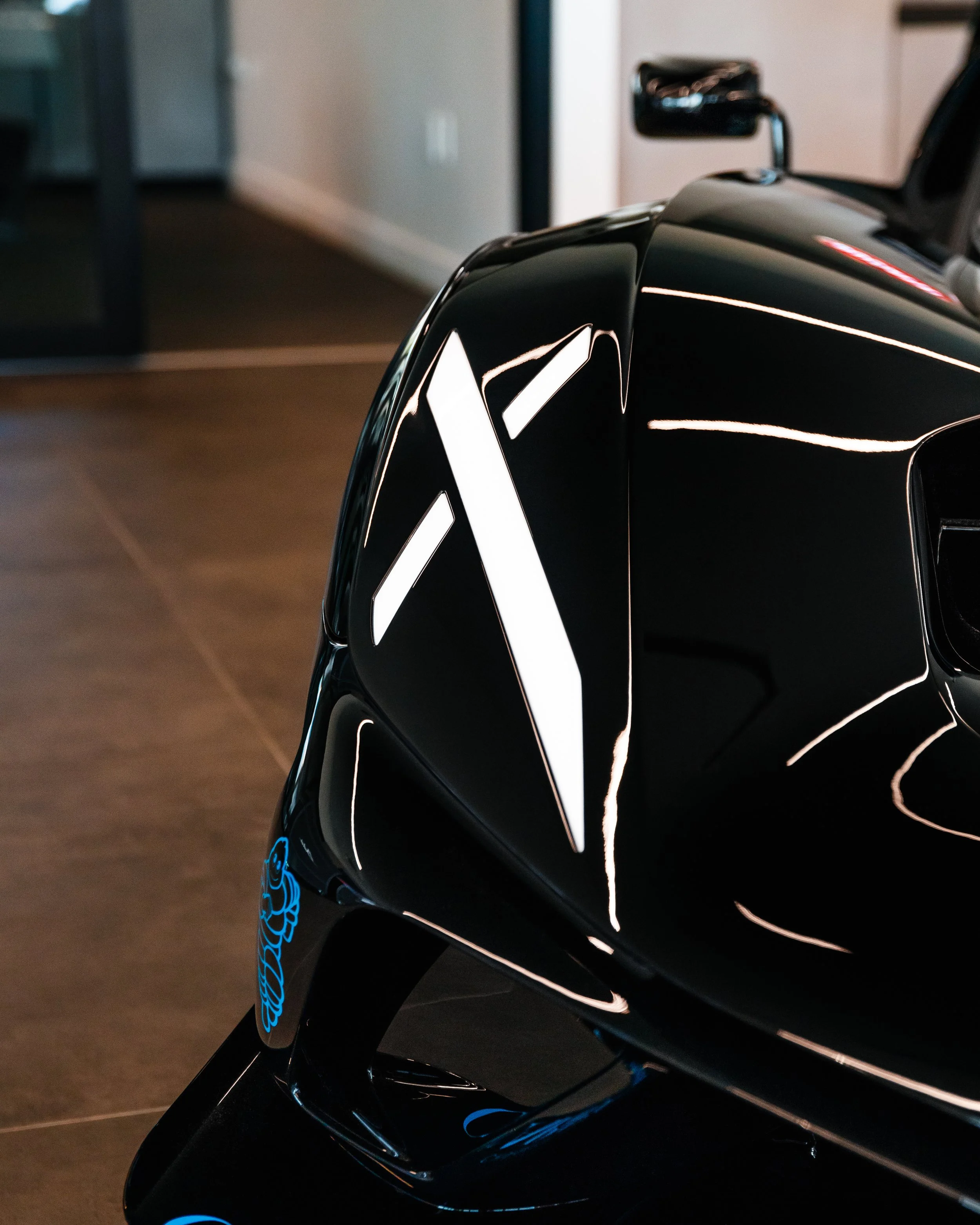Close-up of a black Bugatti Bolide with illuminated white geometric designs on its surface indoors.
