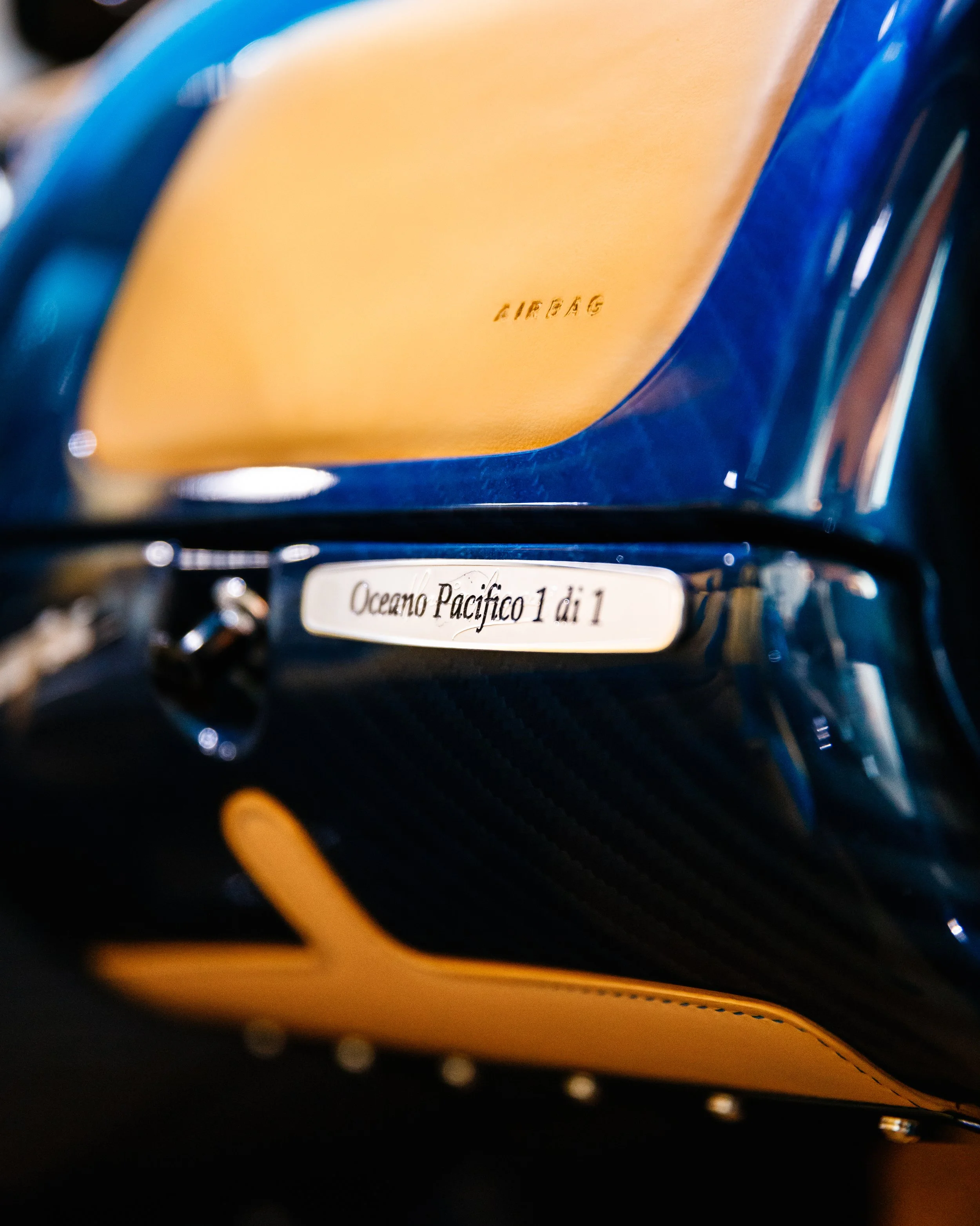 Close-up of a blue and tan interior with a label reading 'Oceano Pacifico 1 di 1' and an 'AIRBAG' marking on the leather.