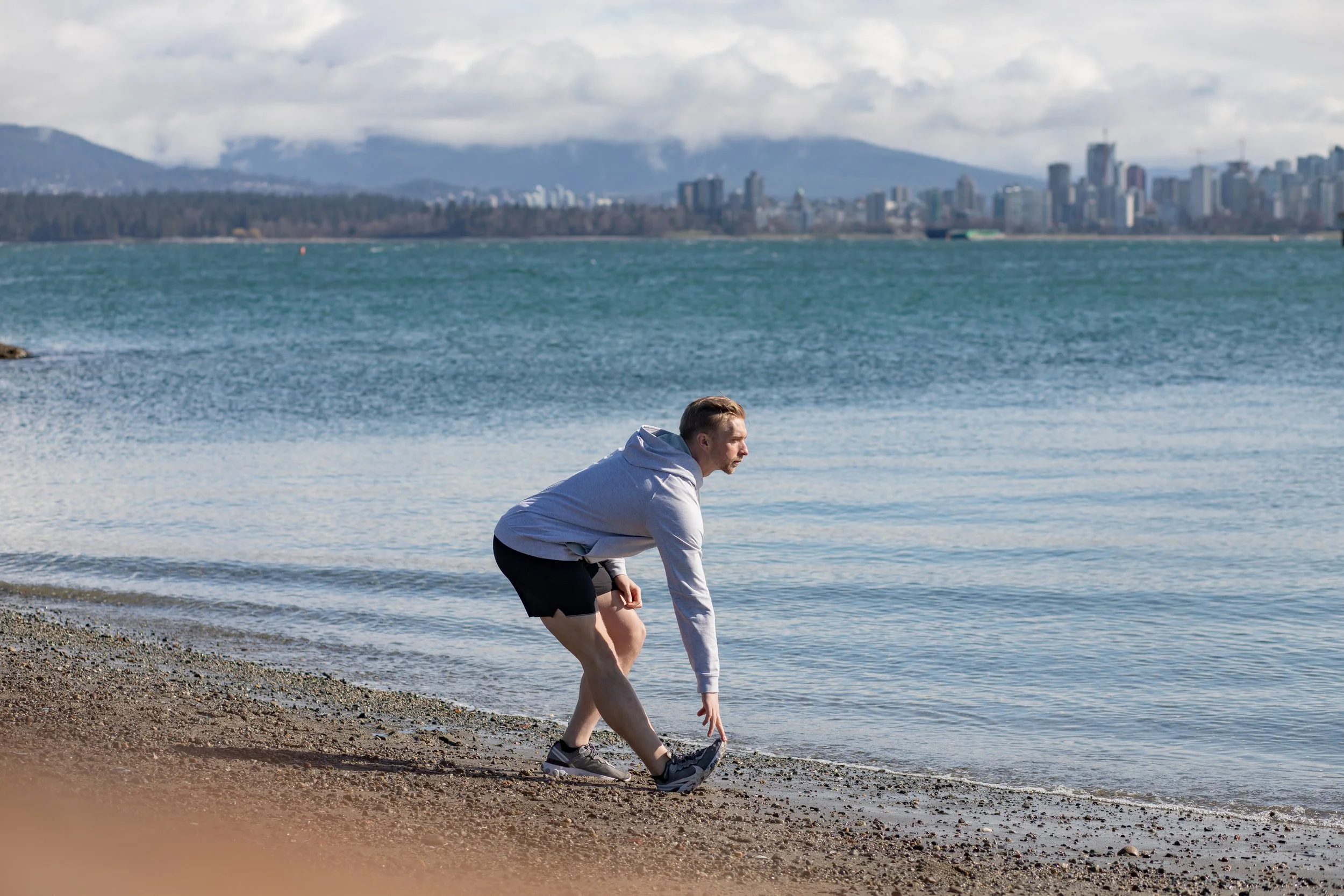 Personal trainer on a Vancouver beach warming up for a run to improve movement and reduce pain