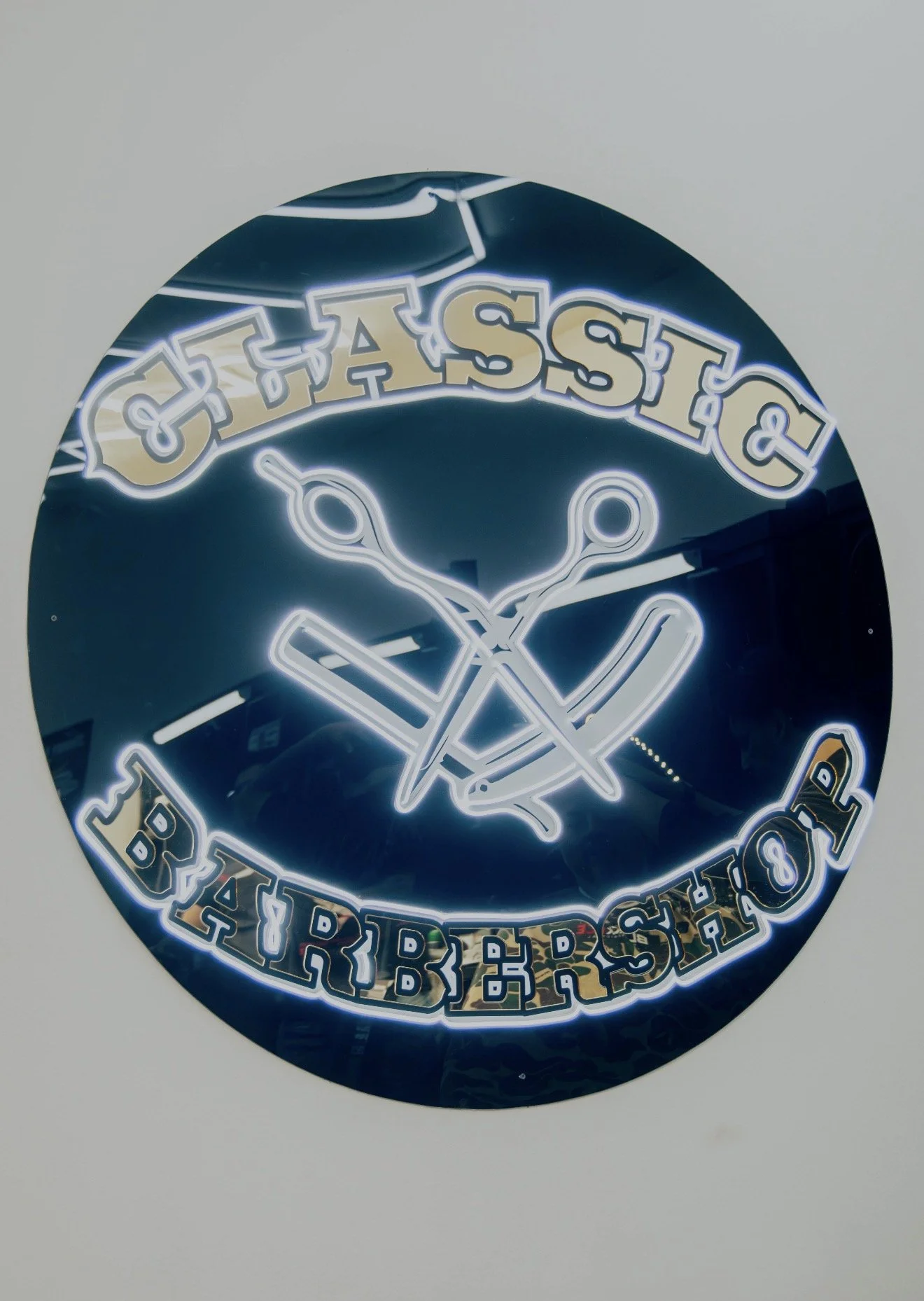 Neon sign with the words 'CLASSIC BARBERSHOP,' featuring barber tools such as scissors and a straight razor.