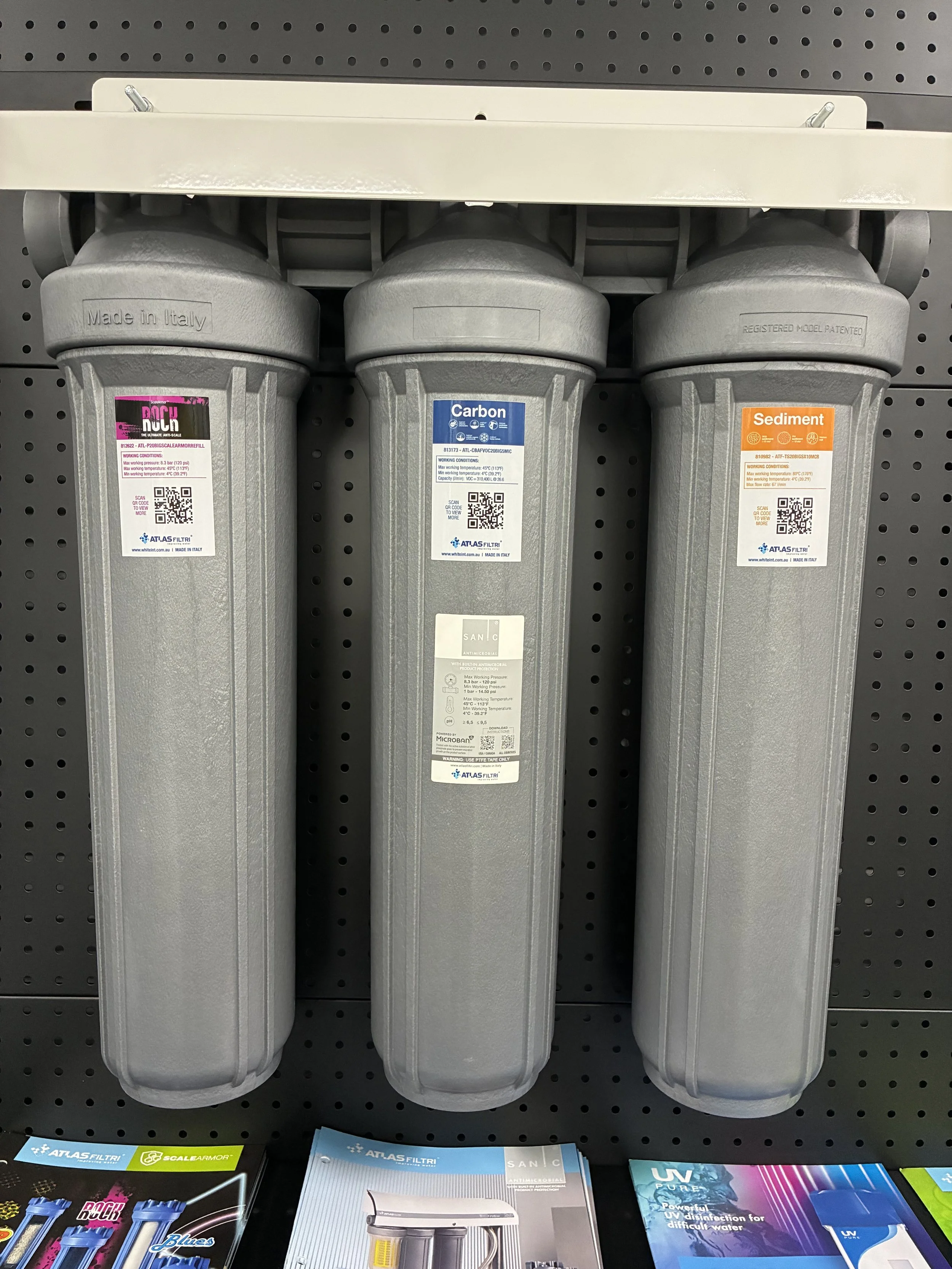 Three large water filter cartridges mounted on a display wall.