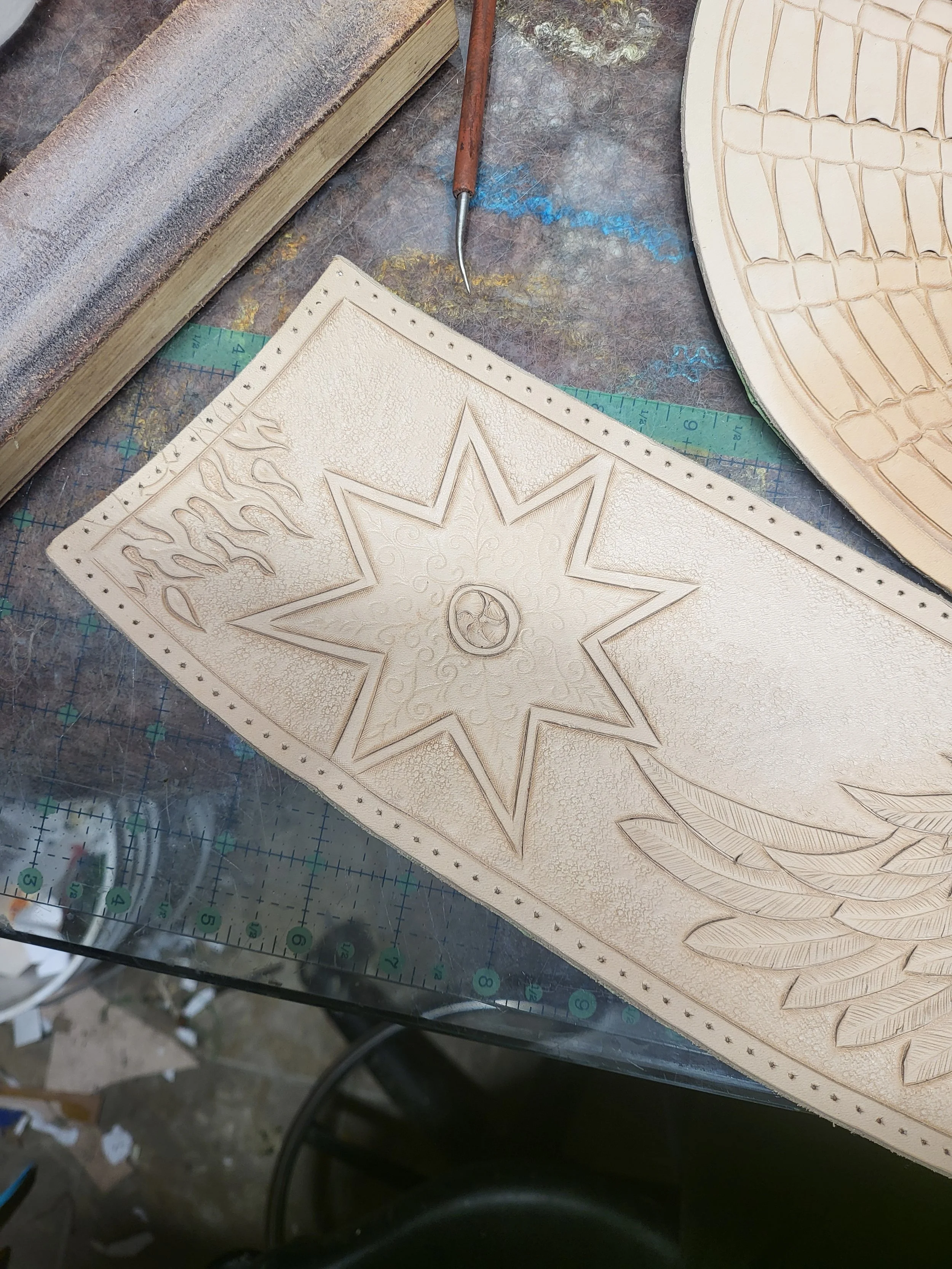 Wood carving of a star with intricate patterns and leaf motifs on a worktable.