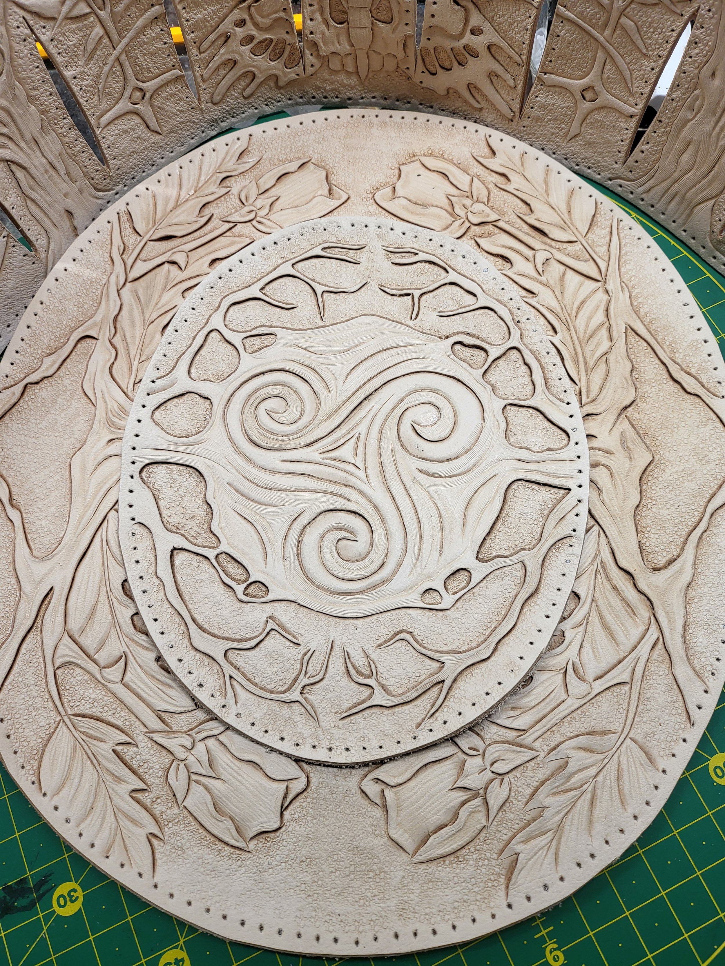 Wooden wall art featuring intricate carved swirling patterns and floral designs in a circular composition.