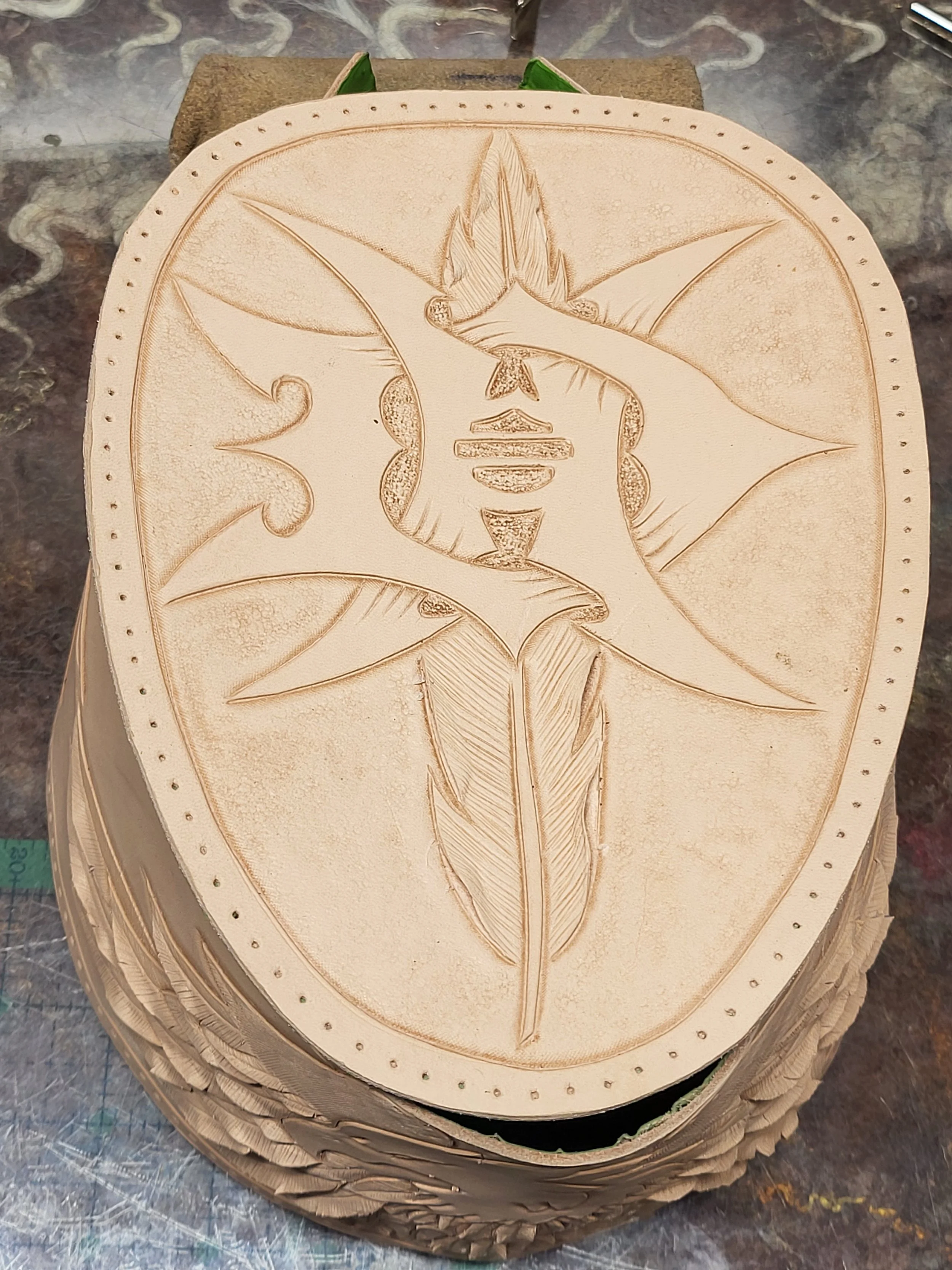 Wood carving of a stylized human face with leaves and abstract shapes surrounding it.