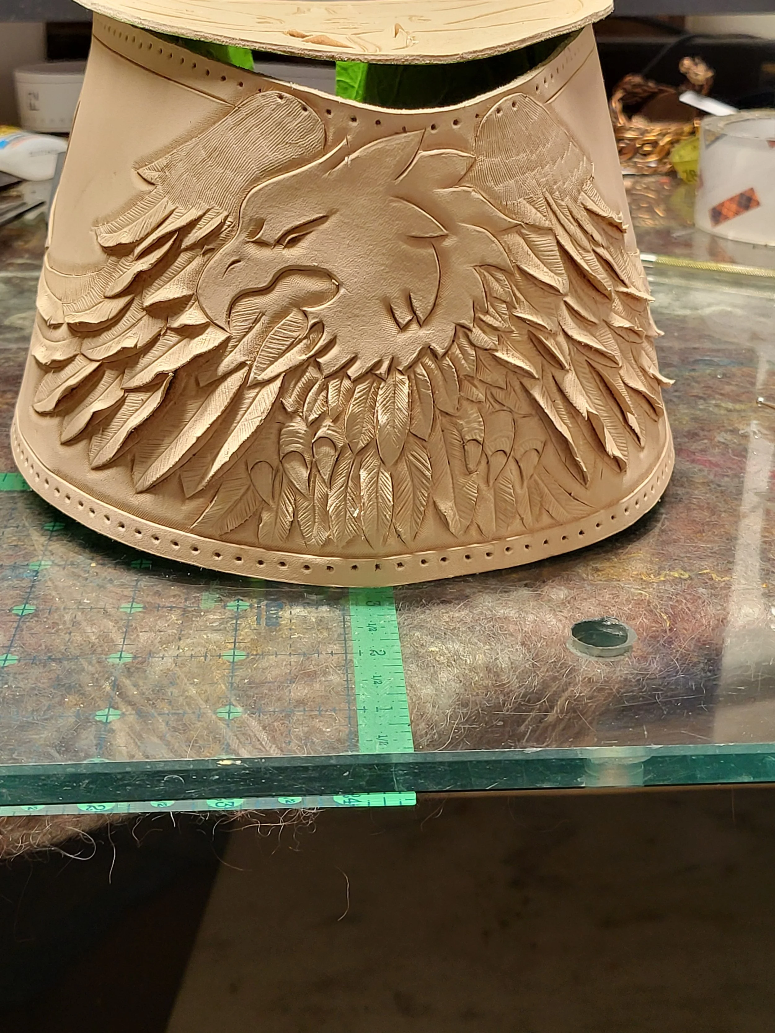 Wooden lampshade with a carved eagle and feather design in the center.