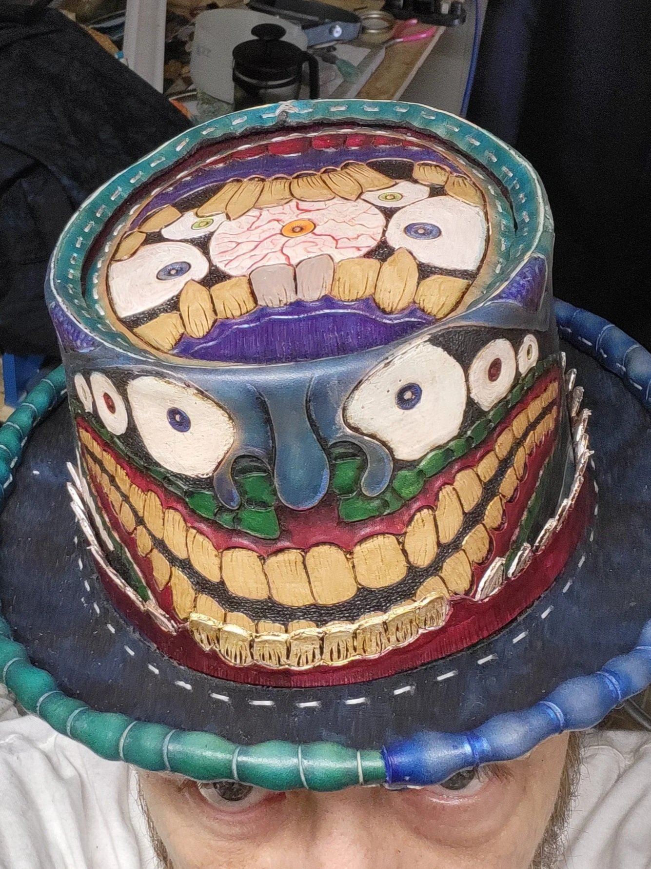 Person wearing a colorful, decorative skull-shaped hat with painted teeth, eyes, and skeletal features. The hat resembles a Day of the Dead sugar skull with vivid colors and intricate patterns.