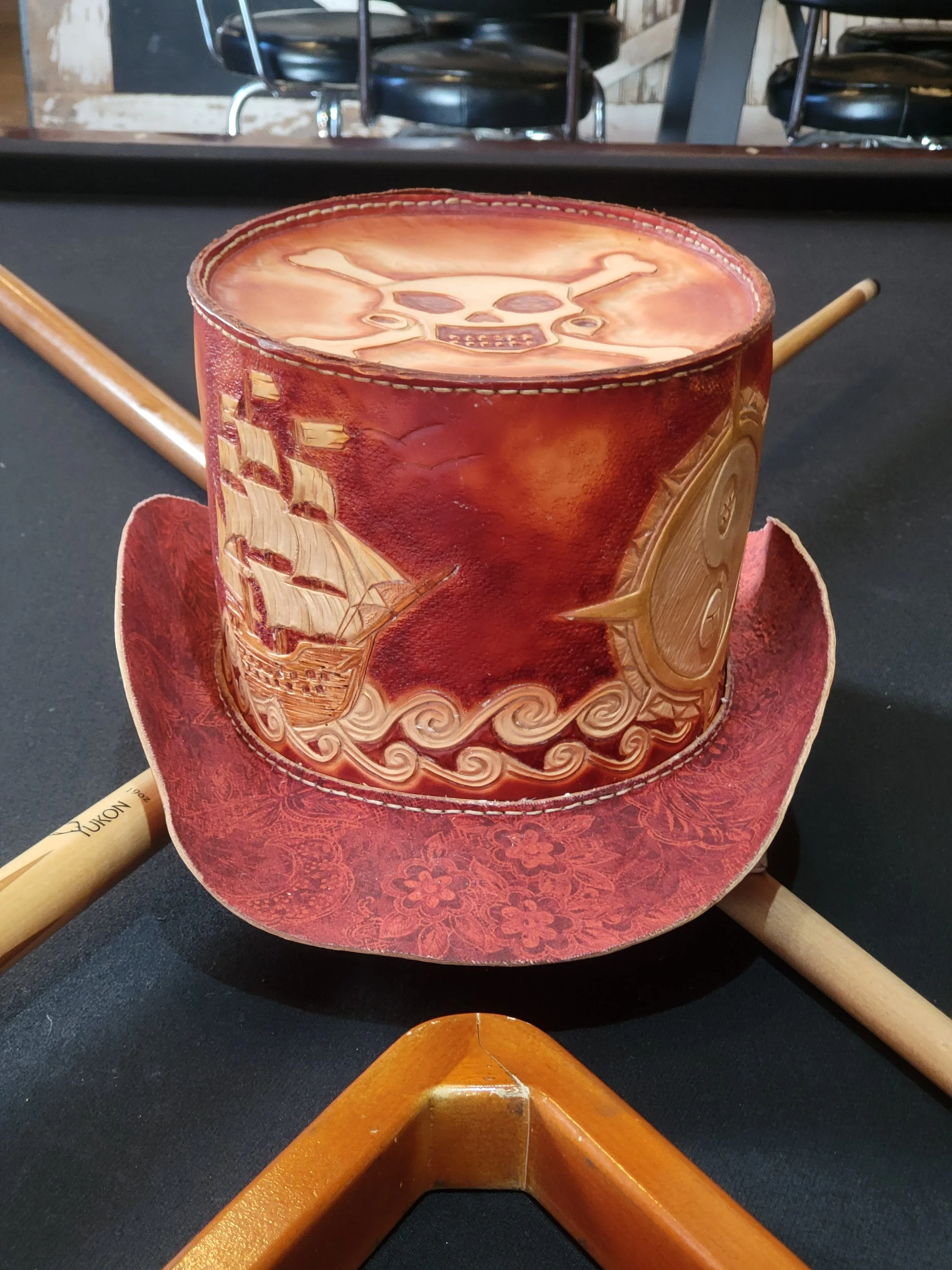 A pirate-themed drink in a cup designed to look like a pirate hat with a skull and crossbones on the top, placed on a pool table.