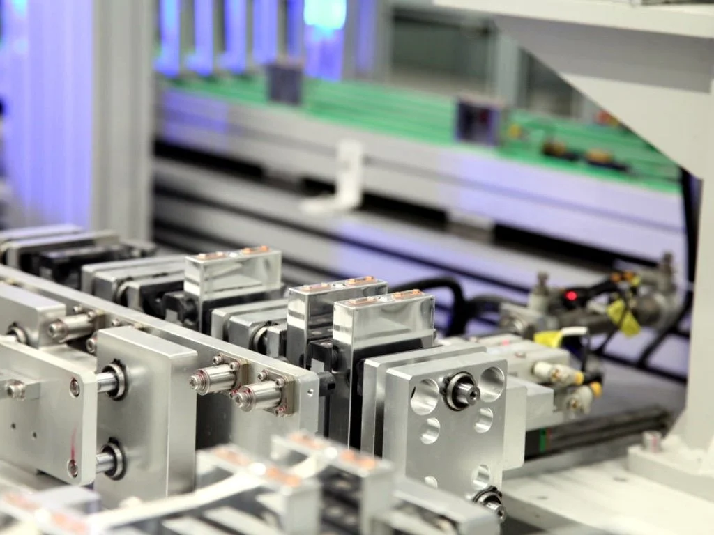 Close-up view of industrial machinery with metallic components and green conveyor belt in the background.
