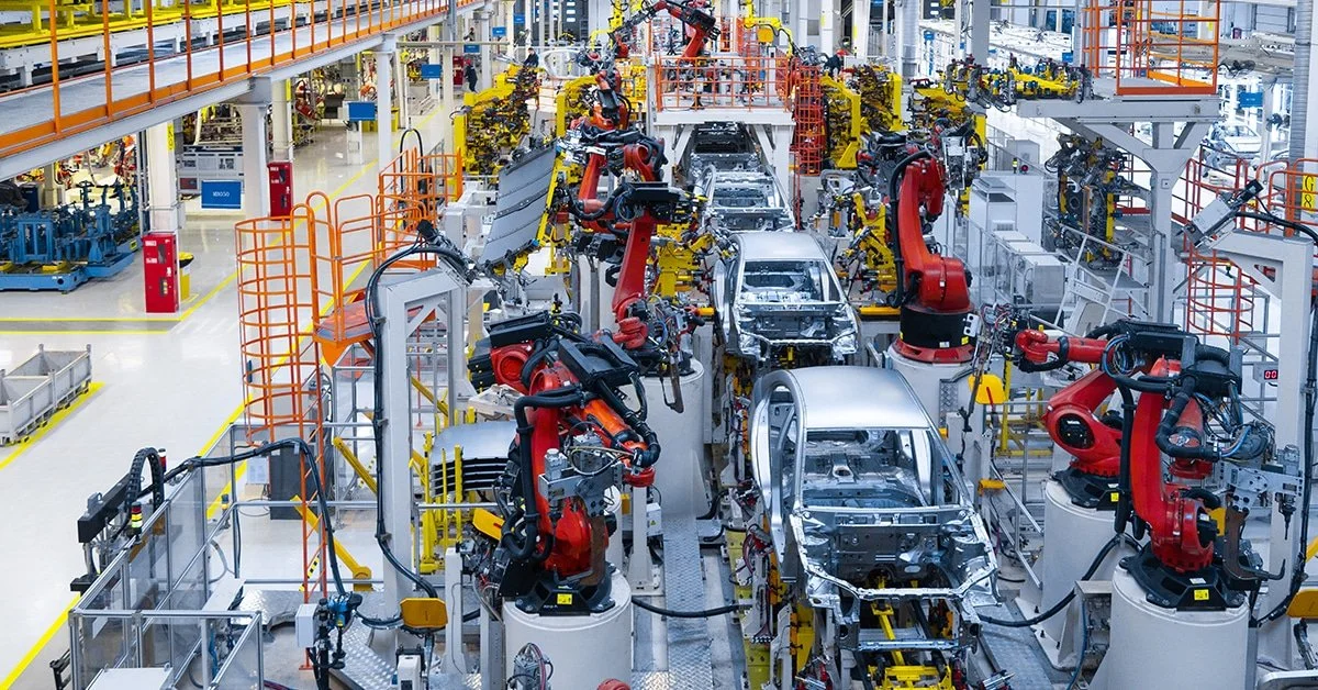 Robots working on assembly line building car bodies in a factory