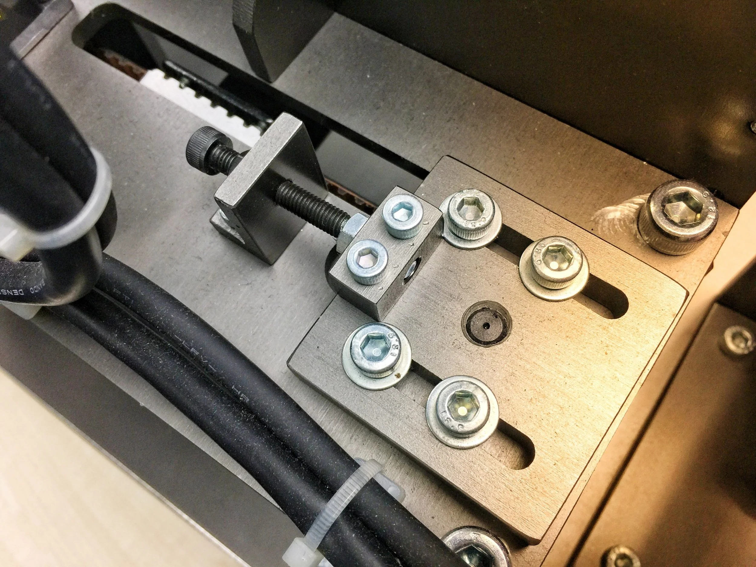 Close-up of metal mechanical parts, screws, and bolts attached to a flat metal surface.