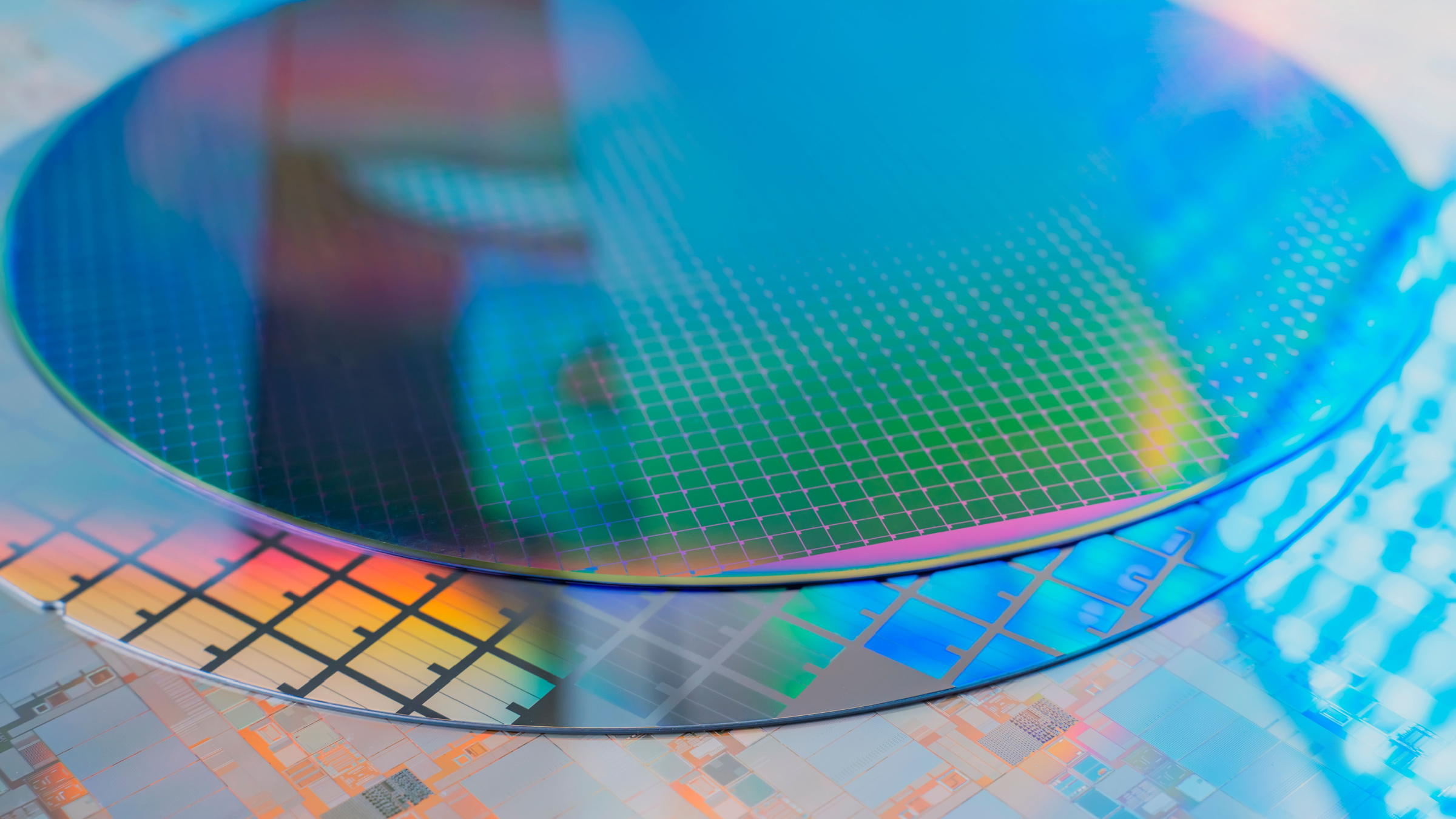 Close-up of multiple silicon wafers with holographic and microscopic patterns, stacked on top of each other.